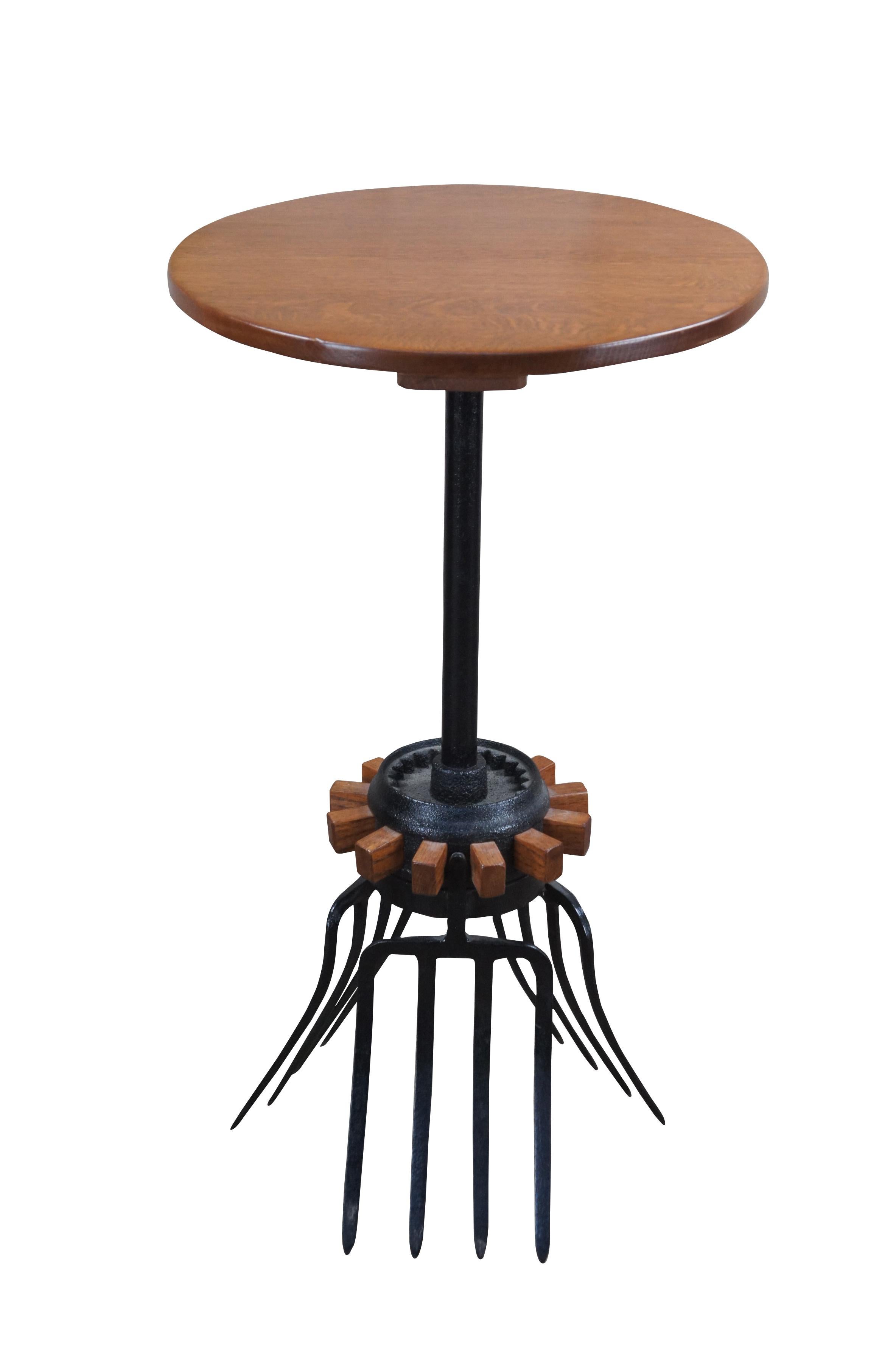 Late 20th Century industrial farmhouse bistro side or end table.  Features an oak top over a cast iron wagon wheel and tripod pitchfork base.  A fun addition to any space.

Handmade by Matthew John Baker of Dayton, Ohio (B, 1956). Matthew