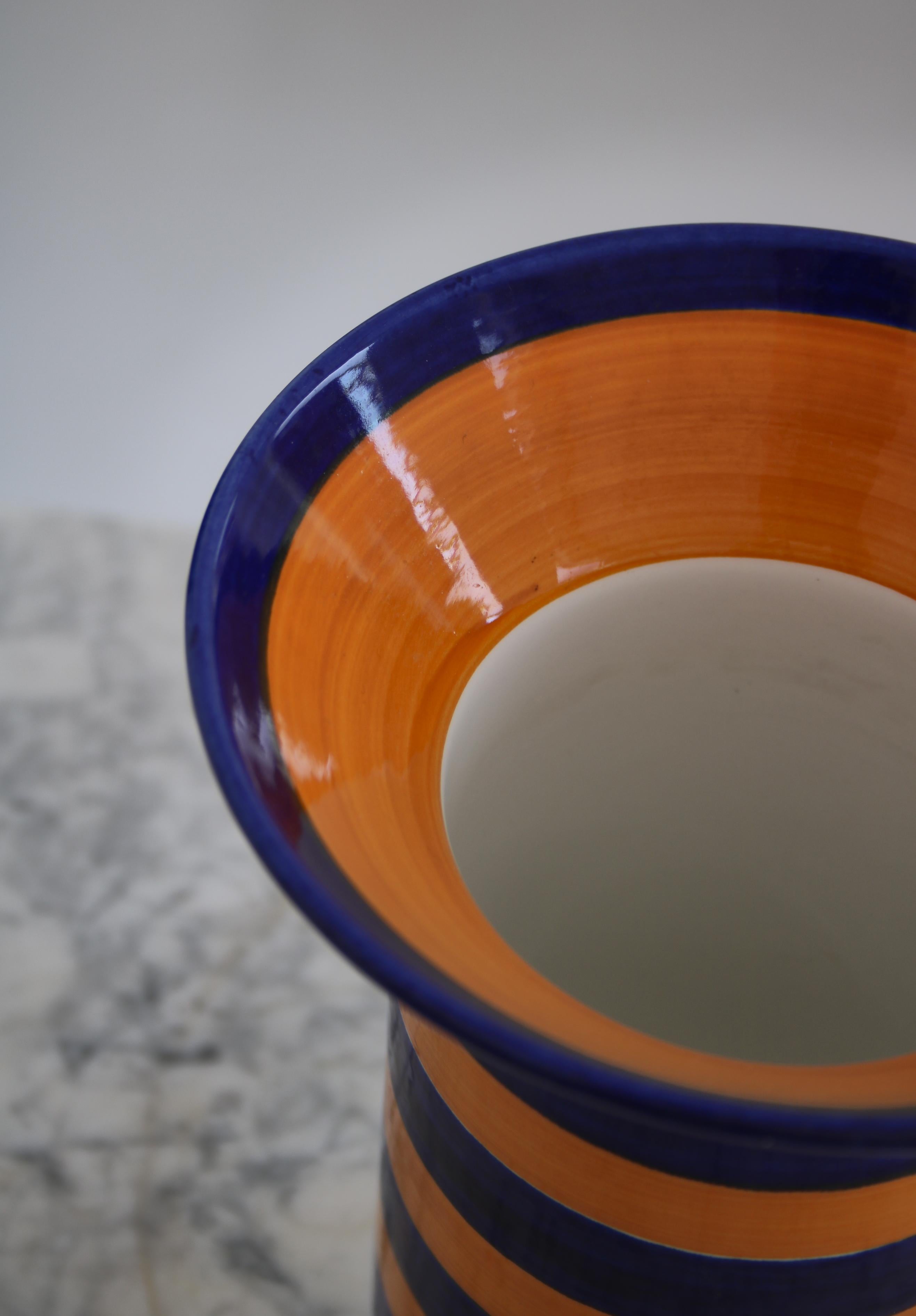 Wonderful hand painted flintware vase by Marianne Westmann for Rörstrand, Sweden. Decorated with a vivid white glazing and blue and orange stripes. Stamped underneath.

Marianne Westman (1928–2017) designed many Scandinavian Modern classics for