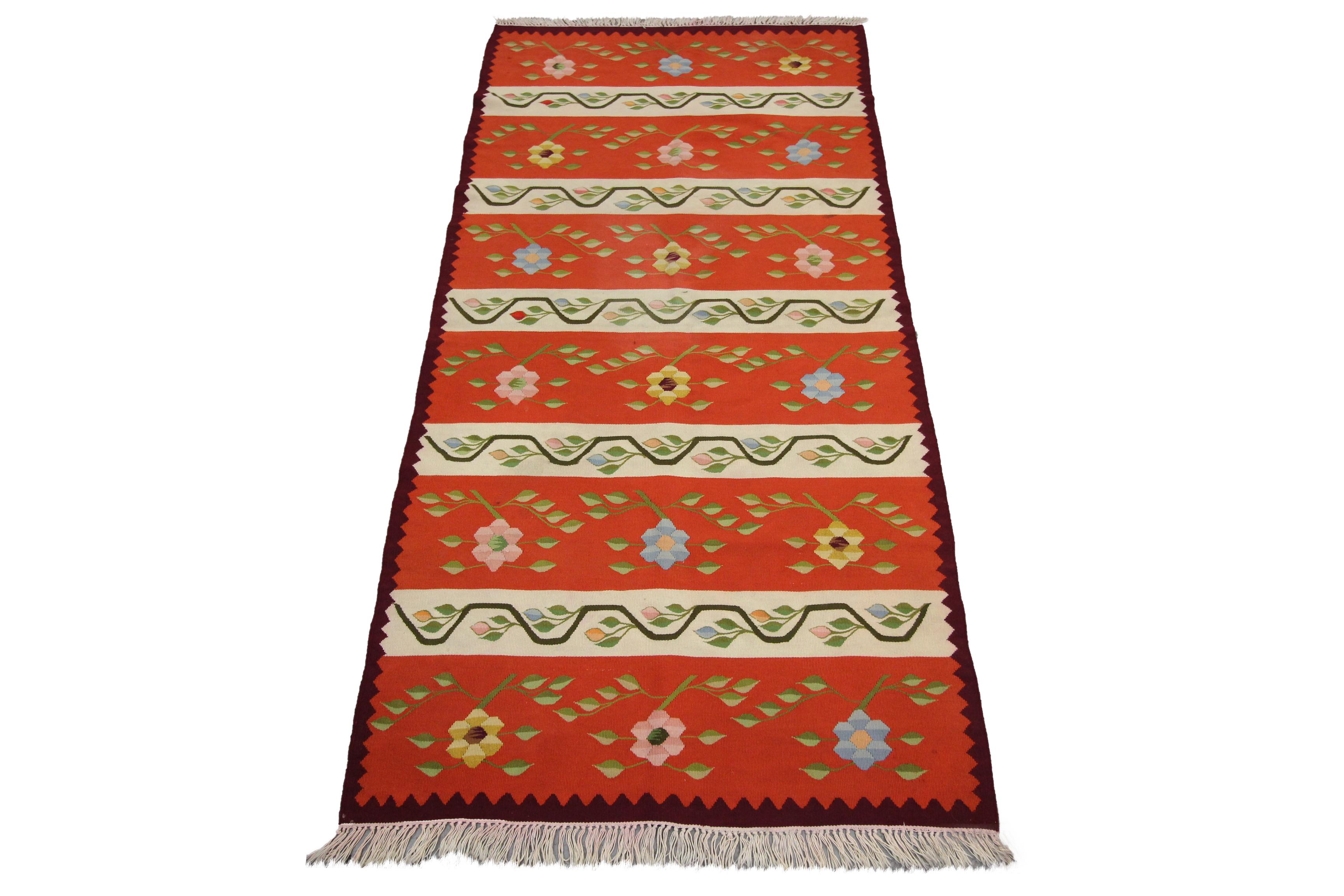 This fine wool rug is a vintage kilim that was woven by hand in the mid-20th century, circa 1960. Woven with a bold red, rust and brown colour palette with a simple stripe design. Both the simple stripe design and bold colour palette make it the