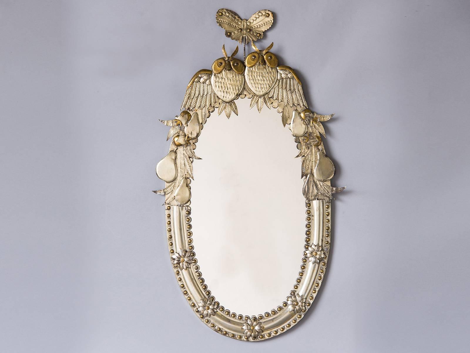 This unique mirror celebrates the union of a couple in marriage using the art of metal working that has been practiced for centuries. The wonderful combination of the oval shape along with the decorative embellishments done in both silvered metal as