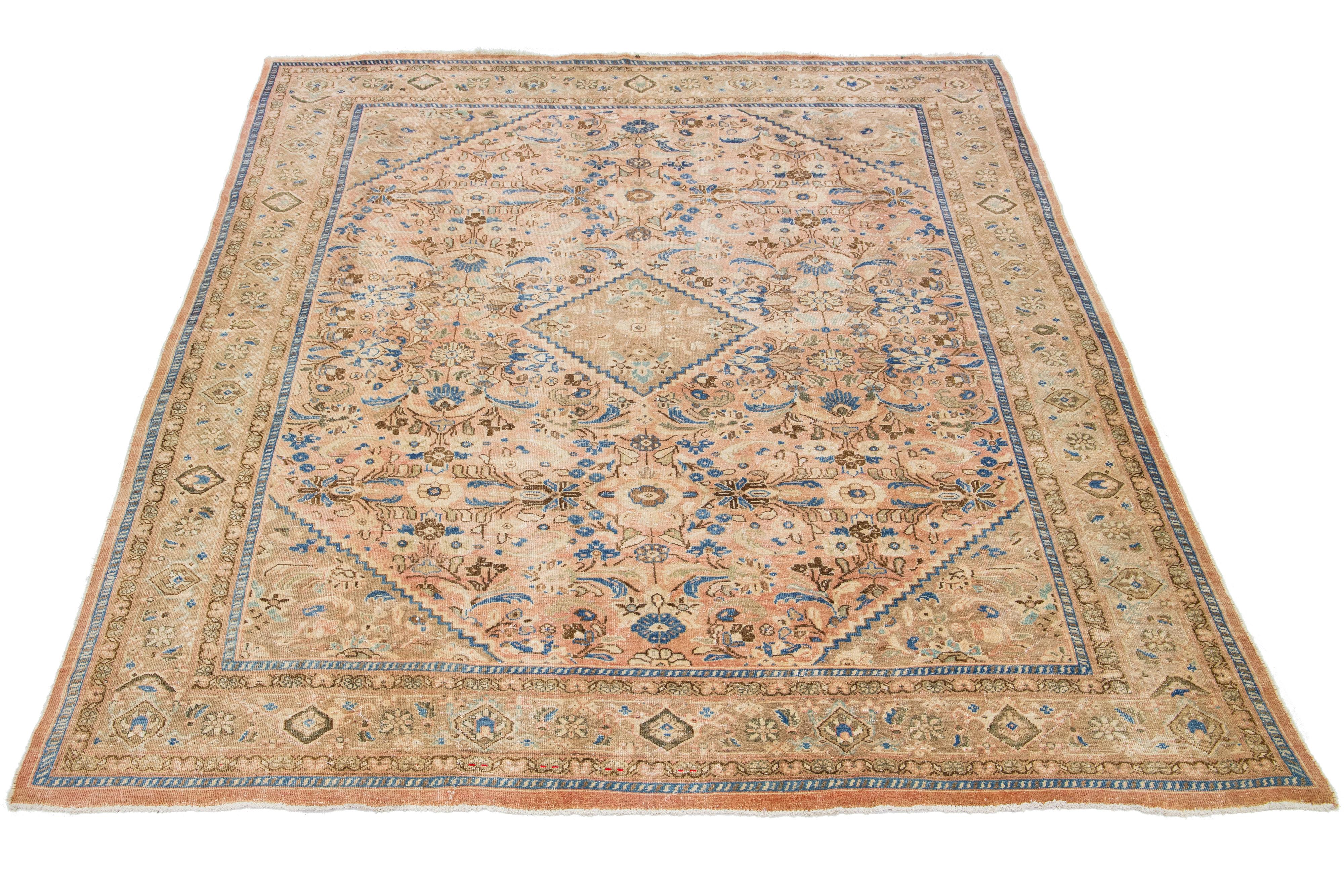 Beautiful antique Mahal hand-knotted wool rug with a peach color field. This Persian rug has blue and brown hues throughout the floral motif.

This rug measures 9'8