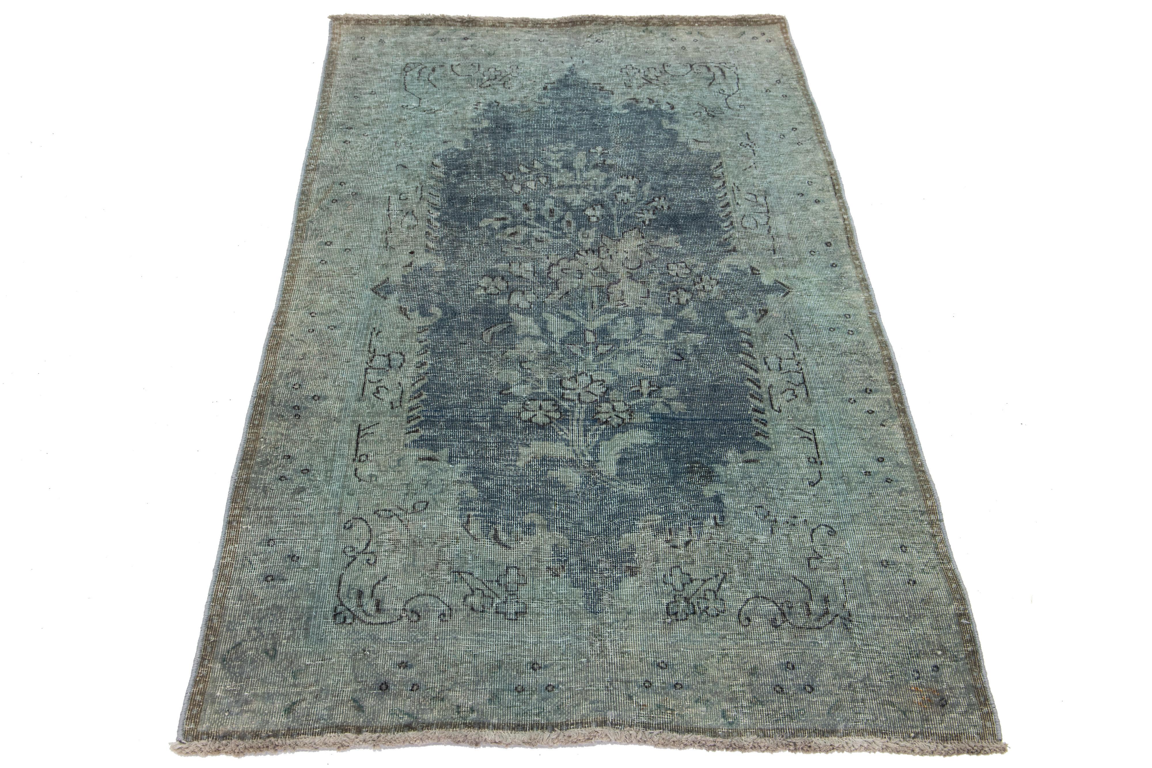 Dieser Vintage-Teppich aus gefärbter persischer Wolle besticht durch ein blaues und graues Farbfeld mit charmanten schwarzen Blumenakzenten.

Dieser Teppich misst 2'10