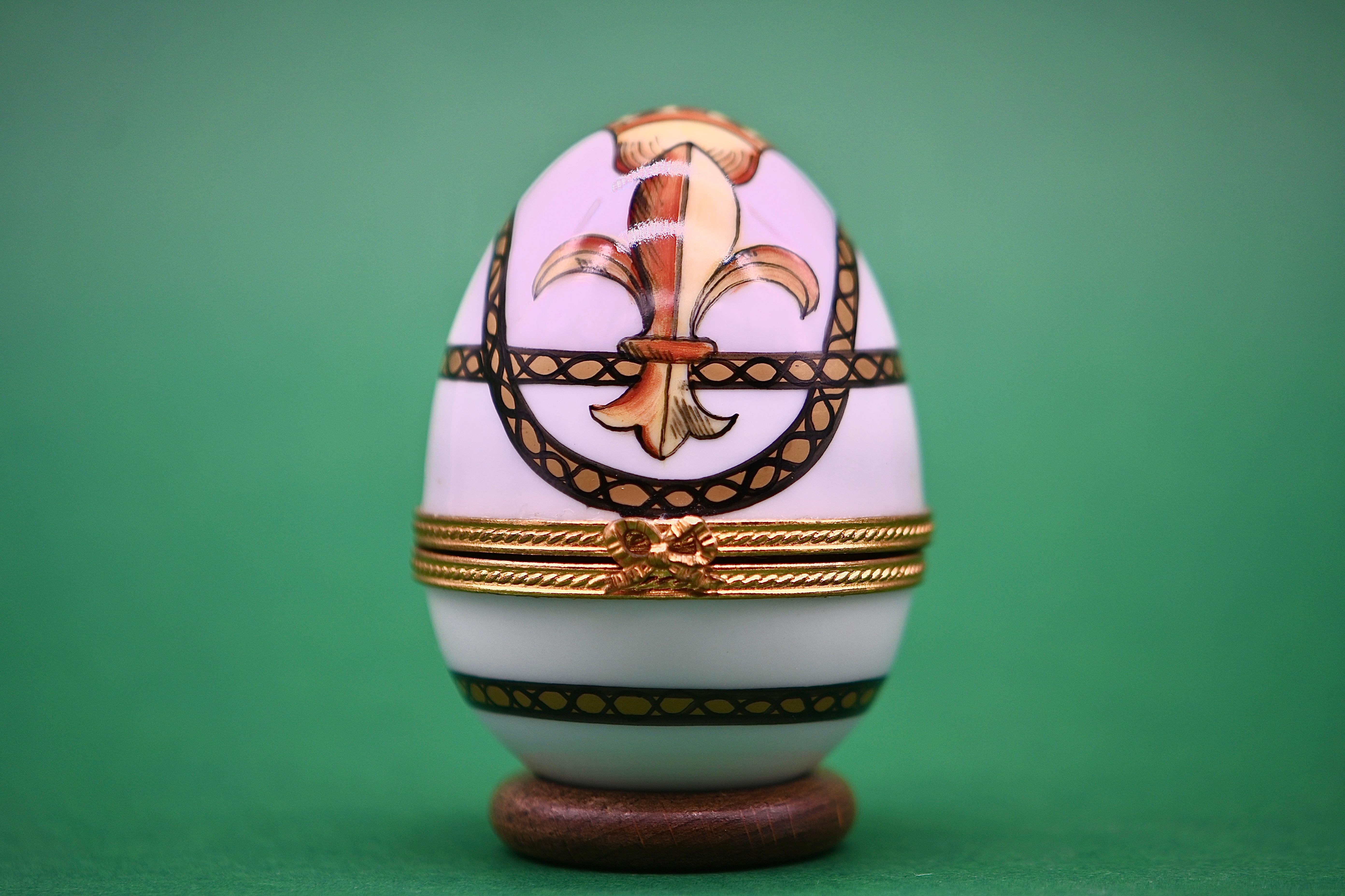 Discover this marvelous egg-shaped clock, crafted in Limoges porcelain and finely hand-painted, signed by the artist. The delicate painting depicts a fleur-de-lis, adding a touch of freshness and elegance to this precious object. The egg can be