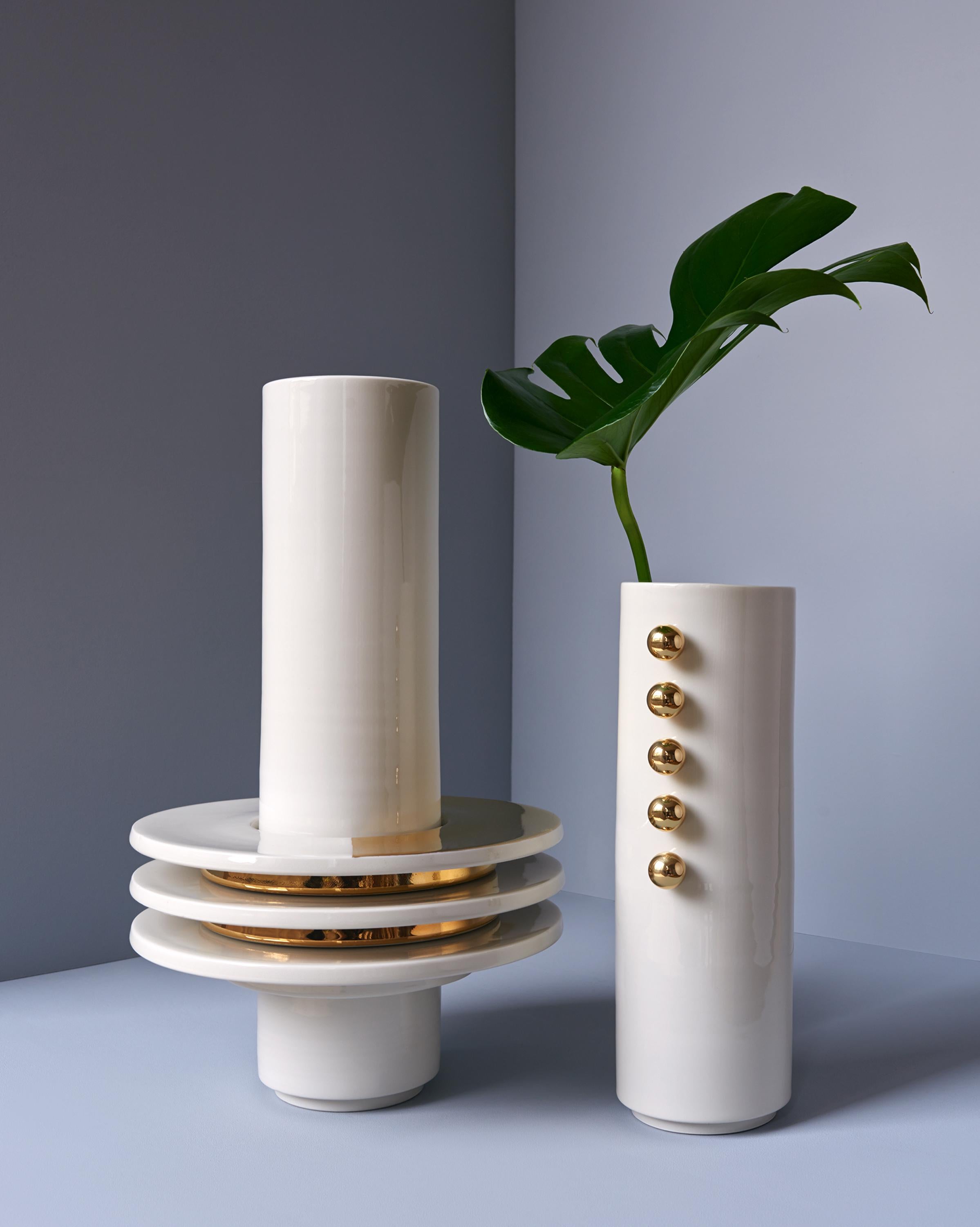 This hand-thrown porcelain vase is a contemporary and functional stand out piece. Glossy white porcelain with five different rings, one with 24-karat gold luster on half the surface, two full gold and two white glossy porcelain. The vase has a size