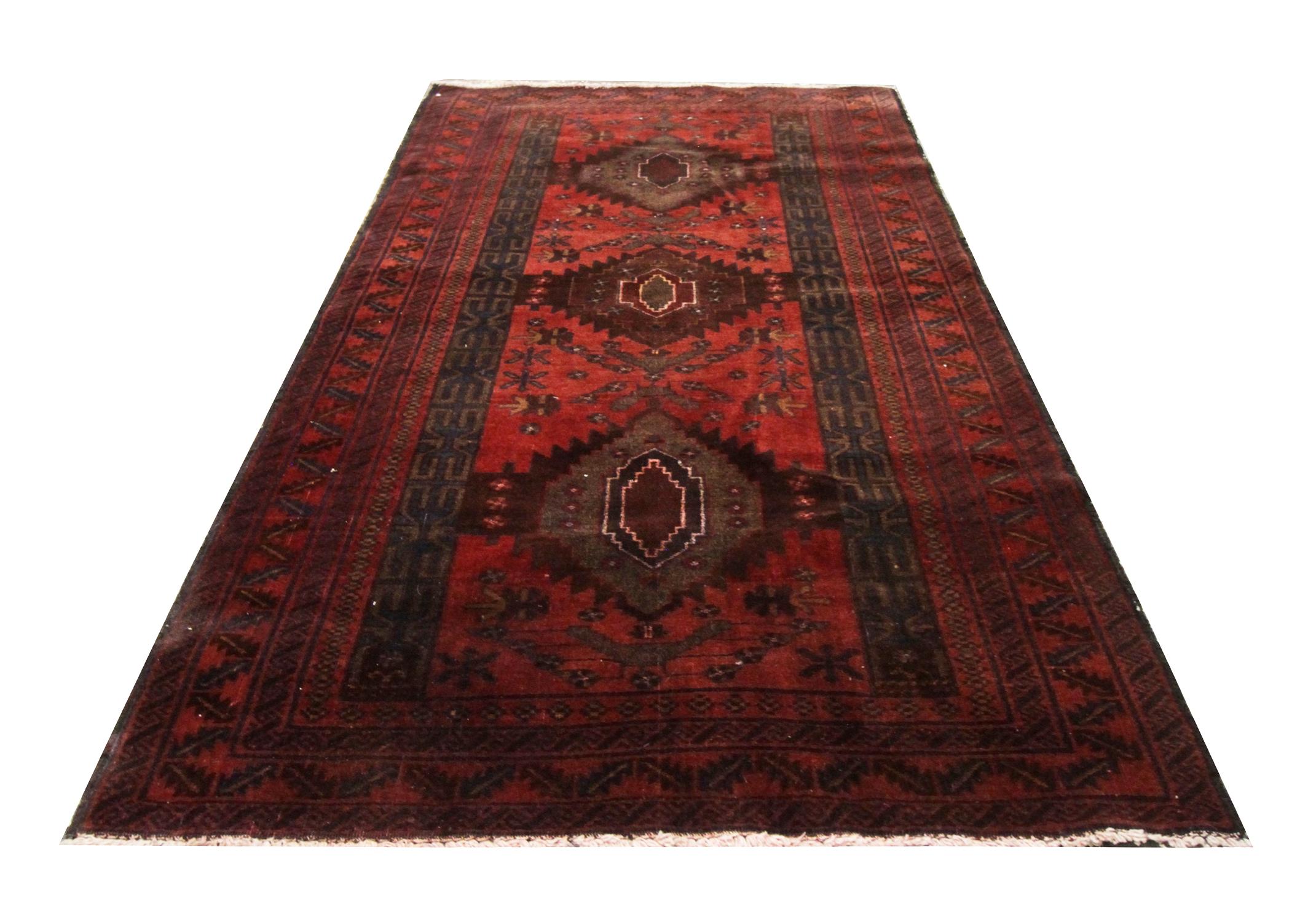 This elegantly woven wool carpet was constructed by hand in the 1960s. The central design has been woven with three large diamond medallions woven with a decorative surrounding design and border. Deep red, brown, black and blue make up the main