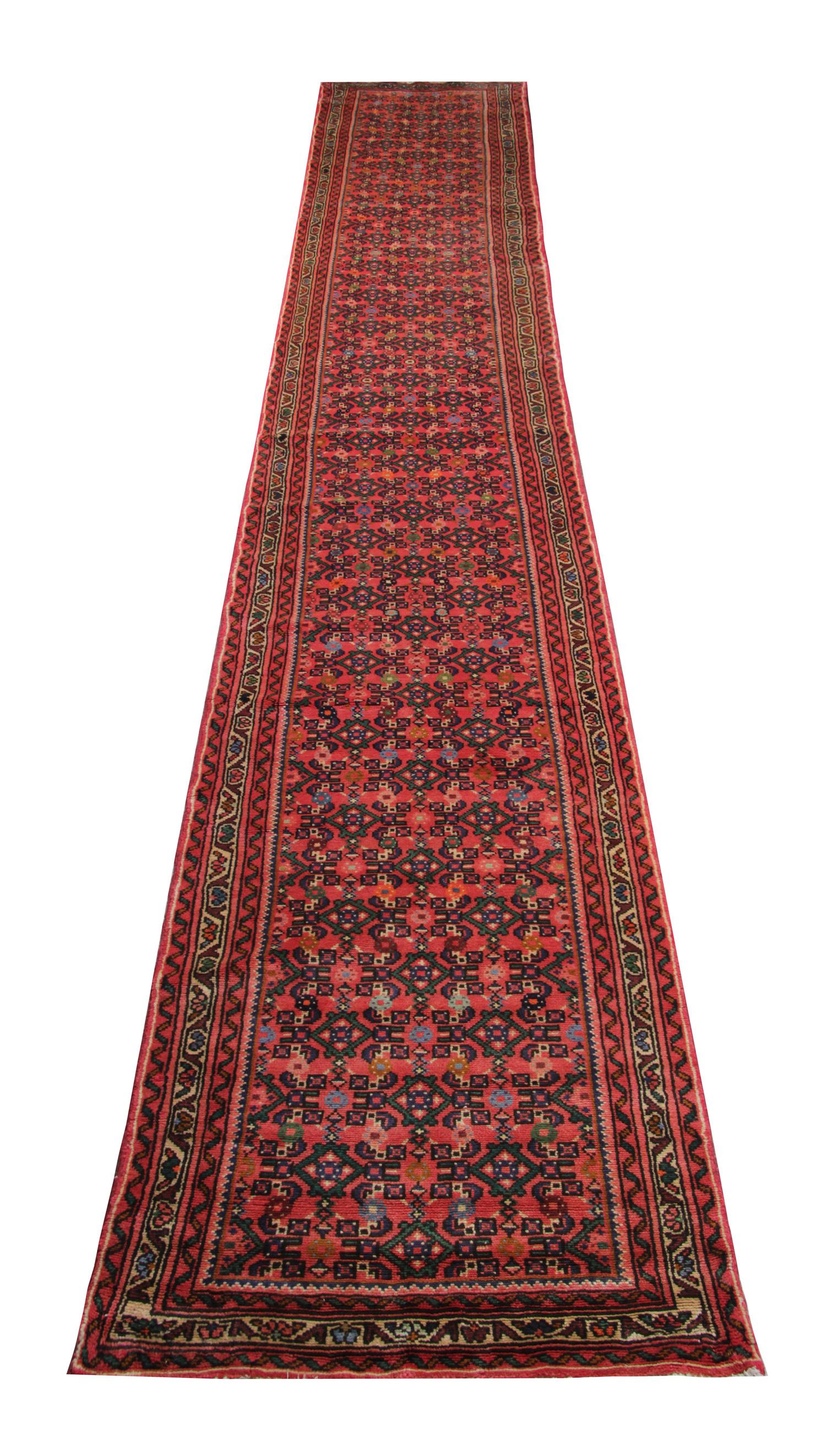 This elegant runner rug was woven by hand in 1950 and features a fantastic repeat pattern design. The central design features a red background with brown and cream accents that make up the design. The framing border pulls the whole design together