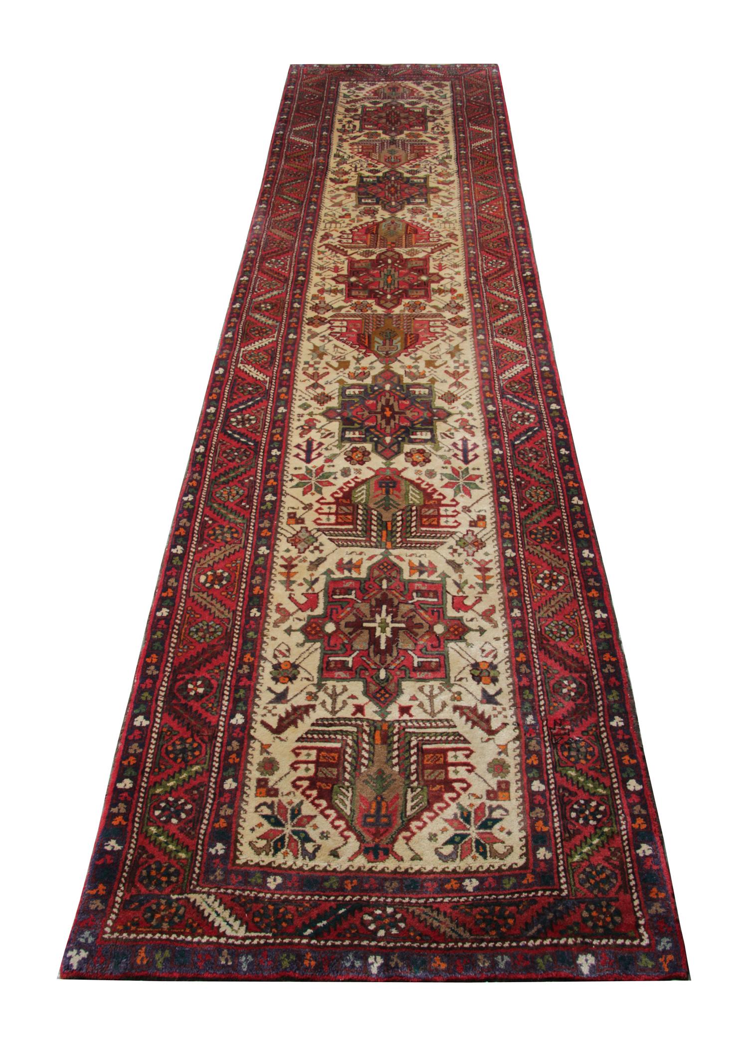 This fine vintage runner rug was woven by hand, with a traditional tribal medallion design that runs through the centre and a highly detailed geometric border. The central pattern sits on a goldfield and is decorated with red, orange, grey and cream