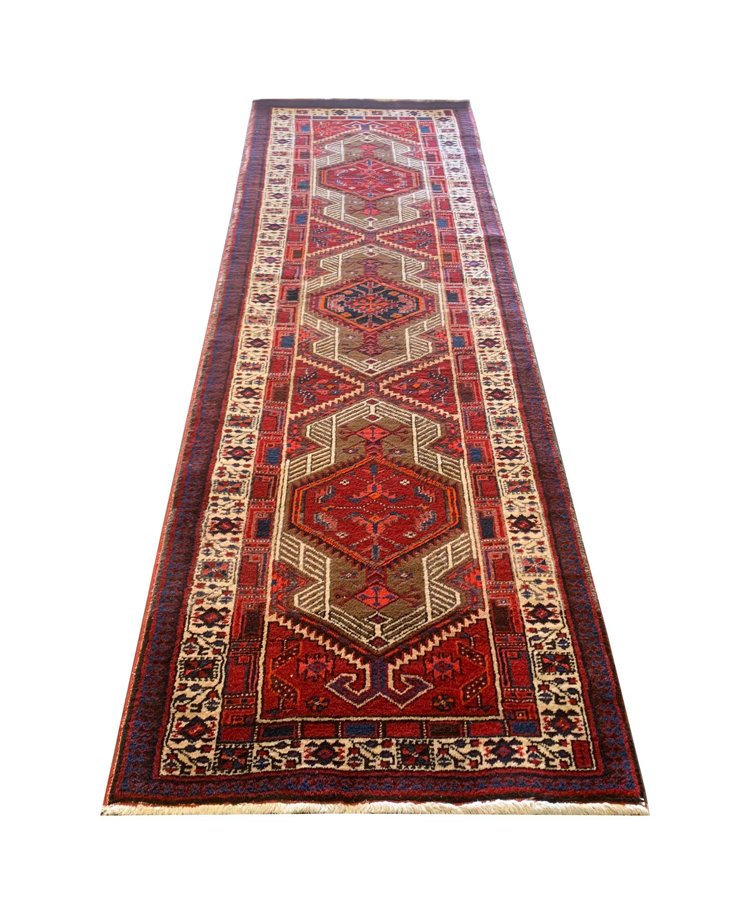 This bold wool rug is an excellent example of runner rugs woven in the early 20th century, circa 1930. The central design features a trio of medallions delicately woven in red and blue accents of beige and cream. An eye-catching repeating pattern