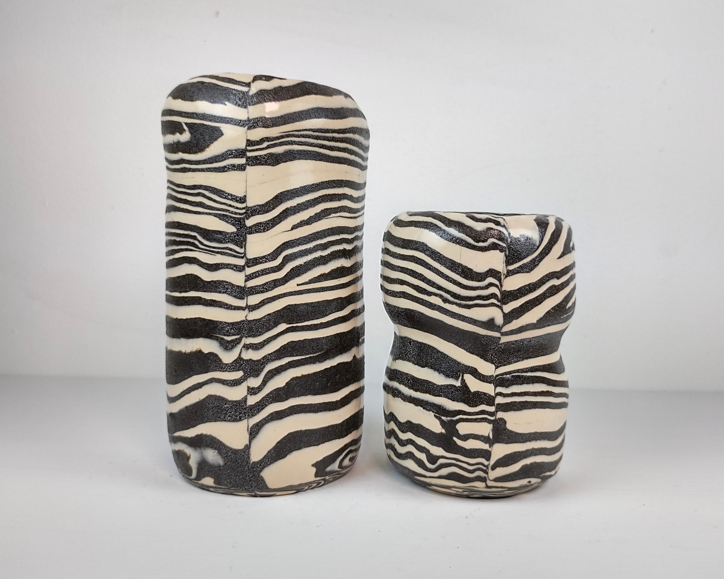 Each vase is formed by putting a slab of alternating clays together before forming into a cylinder and sculpting to the finished shape. Before each firing stage, the clay smudges are sanded and polished away to create sharpness and definition