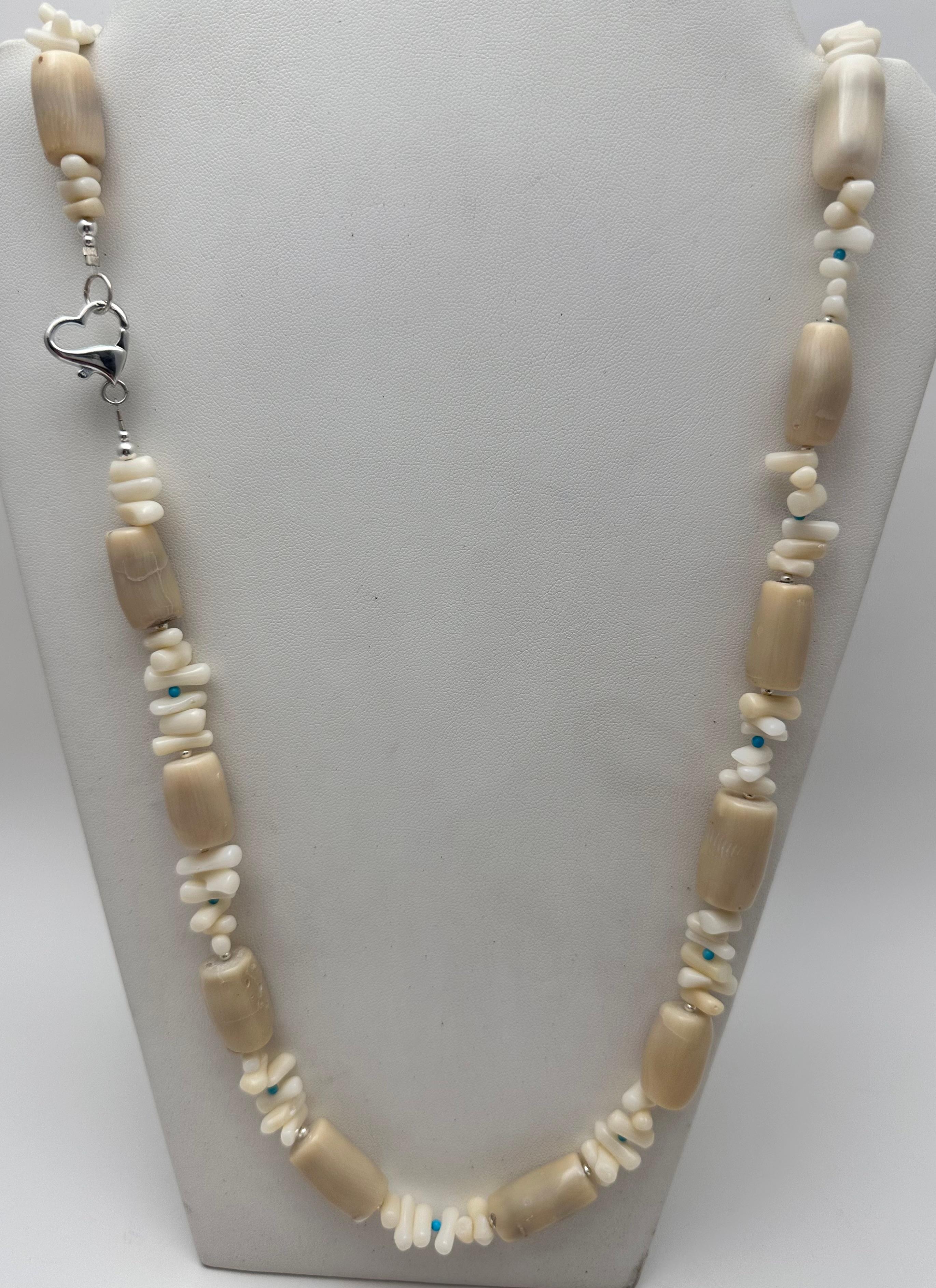 This stunning beaded necklace is a one-of-a-kind piece of handmade jewelry. Crafted from high-quality sterling silver .925, it features lovely beige barrel beads interwoven with coral and sleeping beauty turquoise stones.  The necklace fastens with