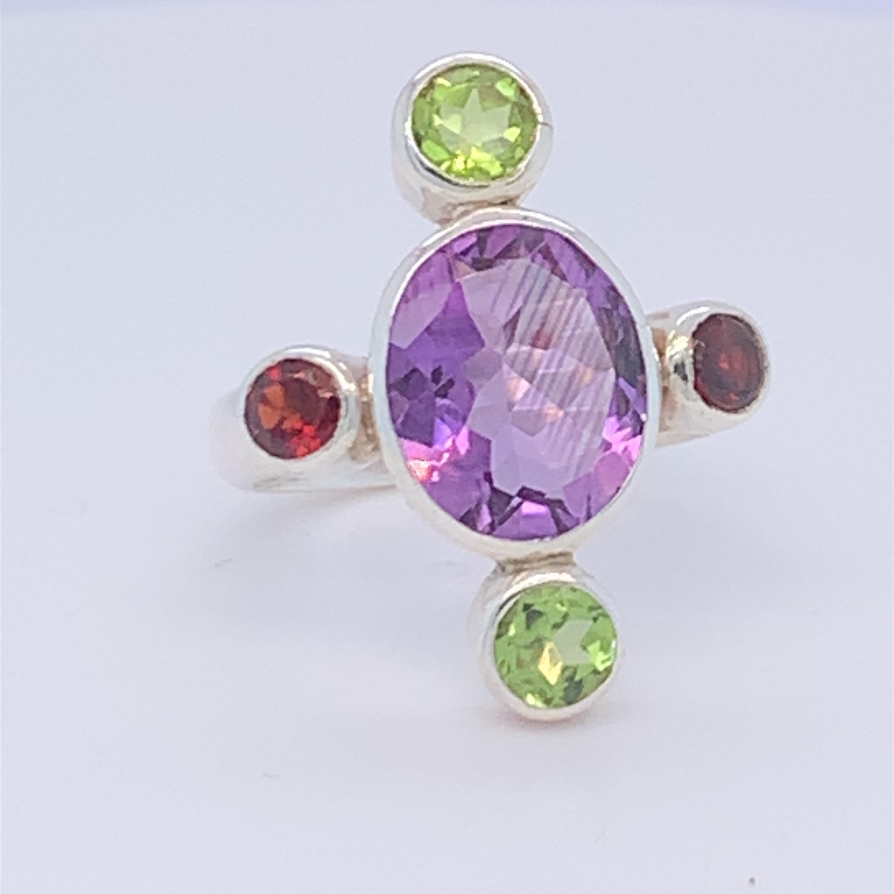 This vibrant five stone ring has oval amethyst as a main stone with peridot and garnet om four sides. It has a unique design and suitable for day wear. Set in sterling silver and hand made by master craftsman.

Total weight of stone: 6.00ct