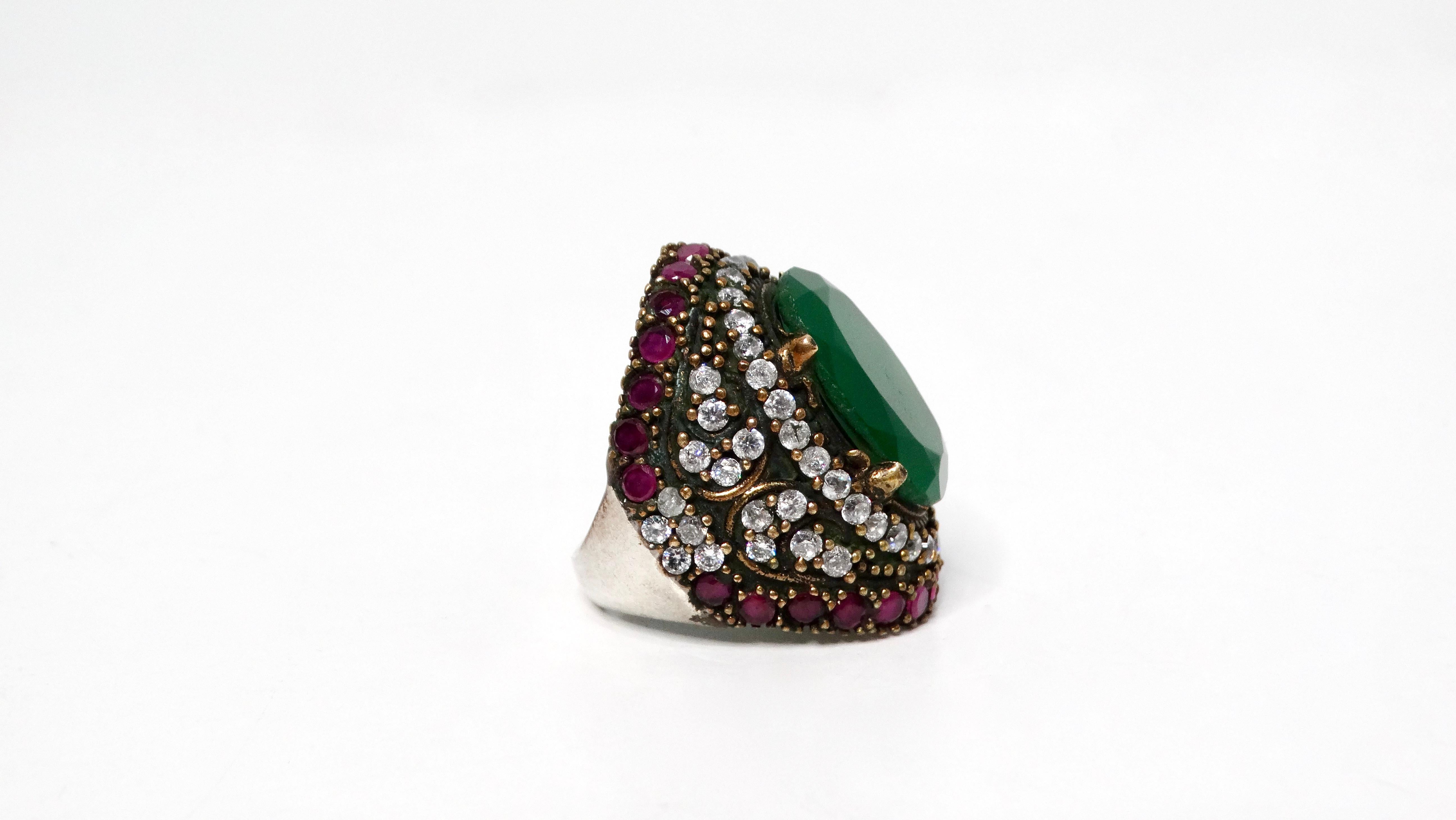 Fai una dichiarazione audace con questo anello da cocktail in costume in argento sterling fatto a mano con smeraldo e strass. Questo anello è un metallo misto di argento e ottone. Caratterizzato da una grande pietra verde simile a uno smeraldo al