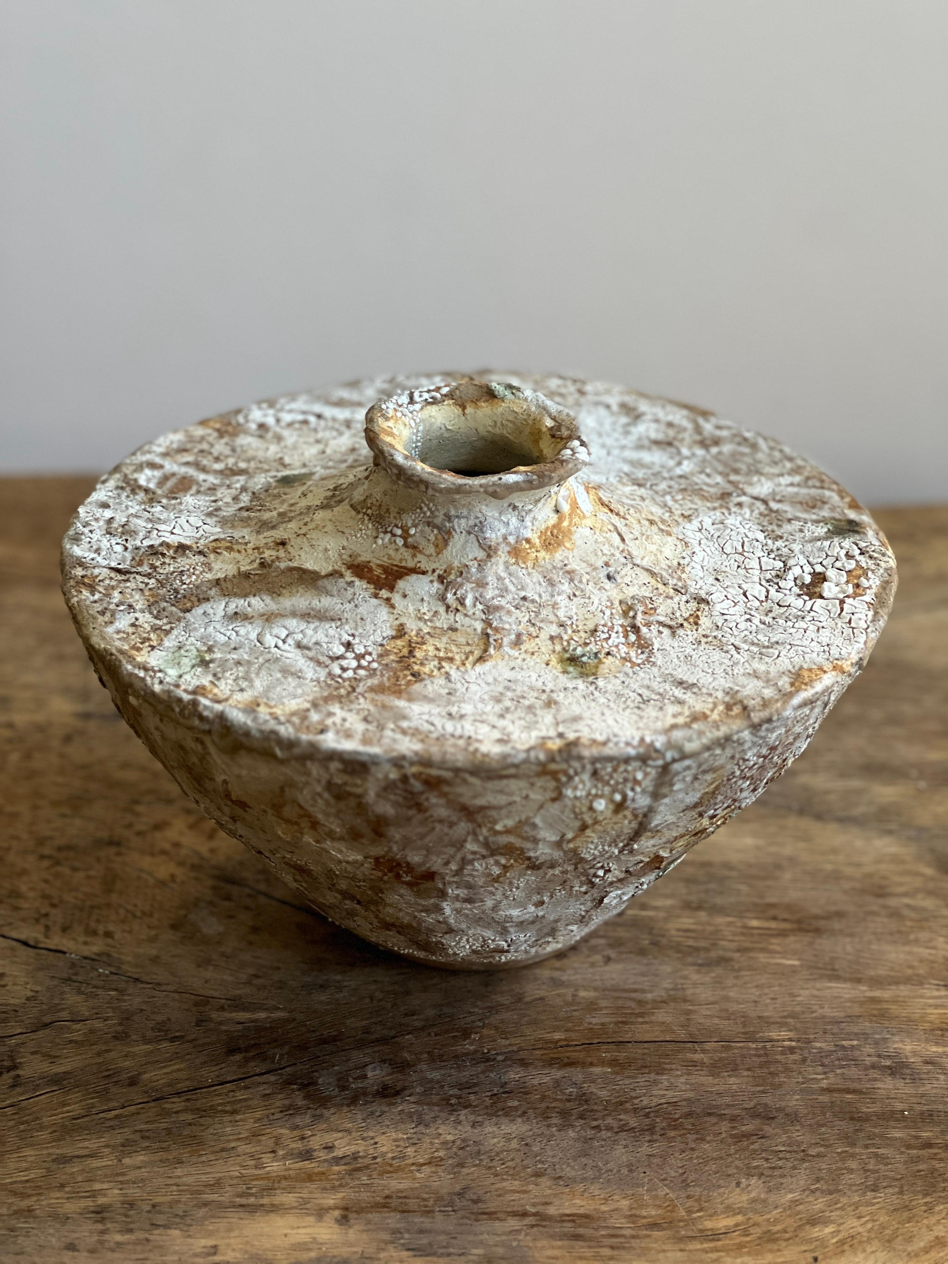 Questo vaso in gres fatto a mano è un pezzo unico che fonde splendidamente texture organica e design artistico. Ricoperta da strati di carta e smalti personalizzati, la combinazione crea una superficie tattile unica, ricca di profondità e carattere.
