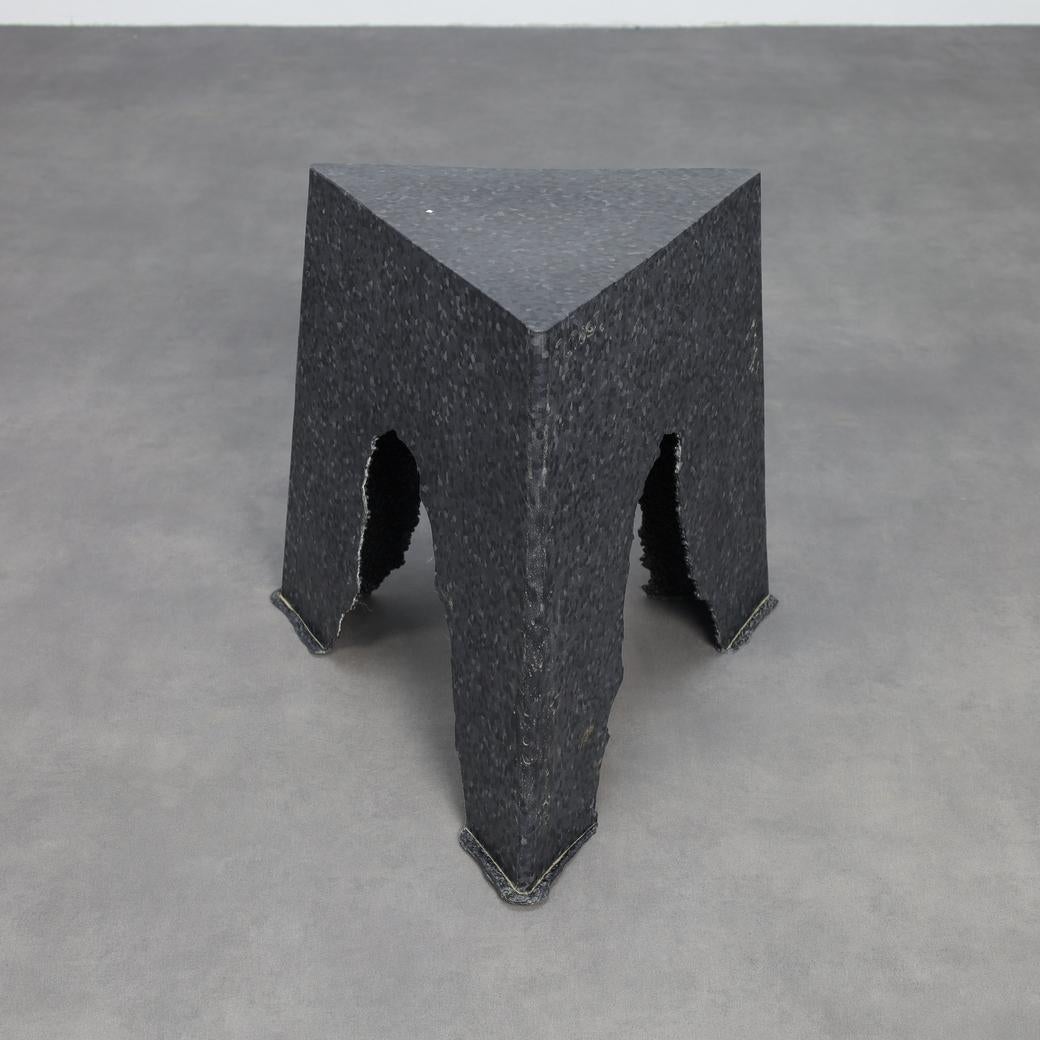 Un tabouret sculptural unique de la série expérimentale Make & Mold de Rutger de Regt, fabriqué à partir de polypropylène recyclé. Avec sa texture brute et sa forme triangulaire audacieuse, la pièce reflète une récupération innovante des techniques