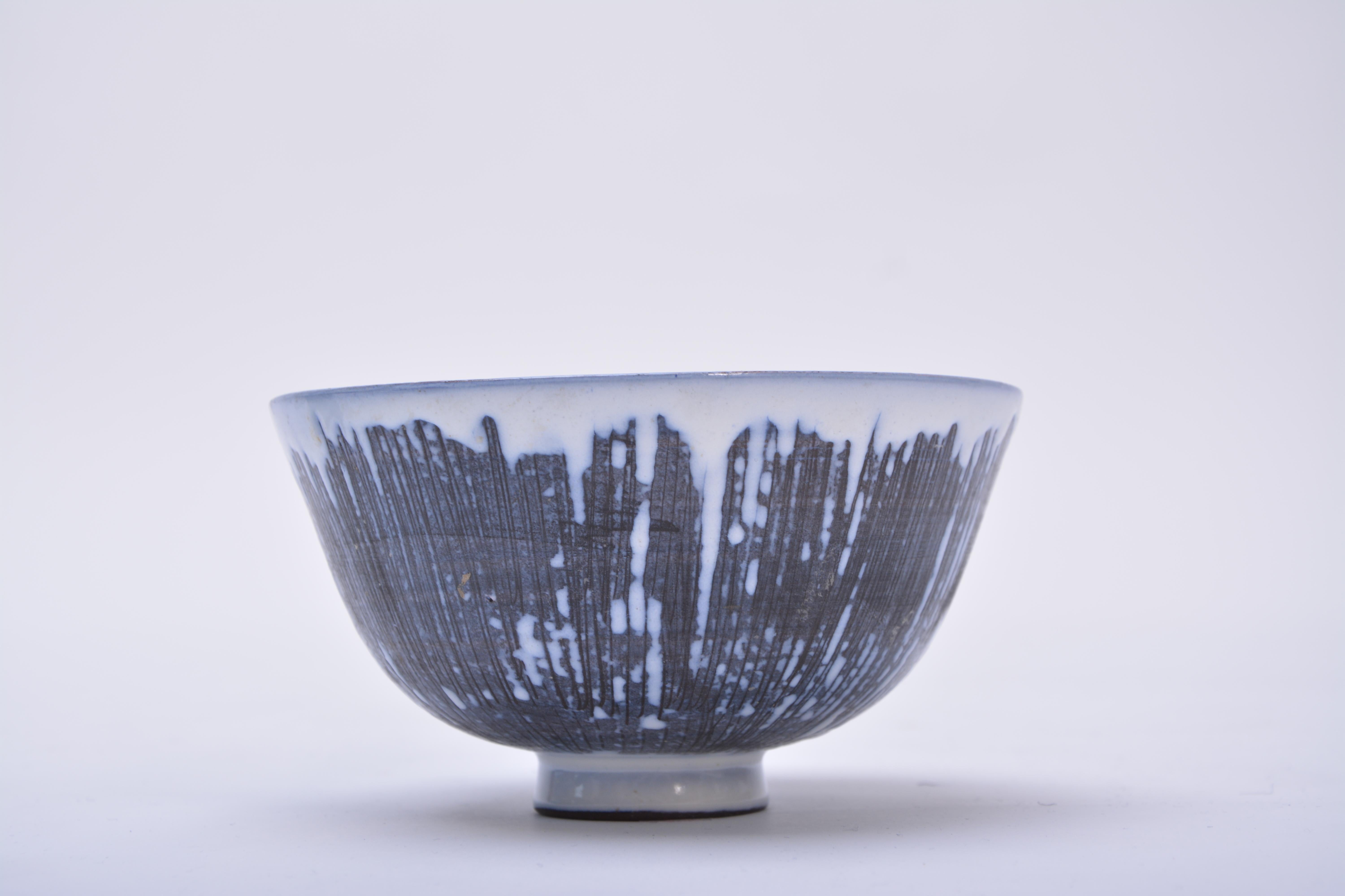 A handmade Swedish Mid-Century Modern ceramic bowl with green, blue, brown, and dark grey glaze creating a geometric pattern. Exterior of the bowl has been decorated with the sgraffito technique that consists of fine lines carved into the background