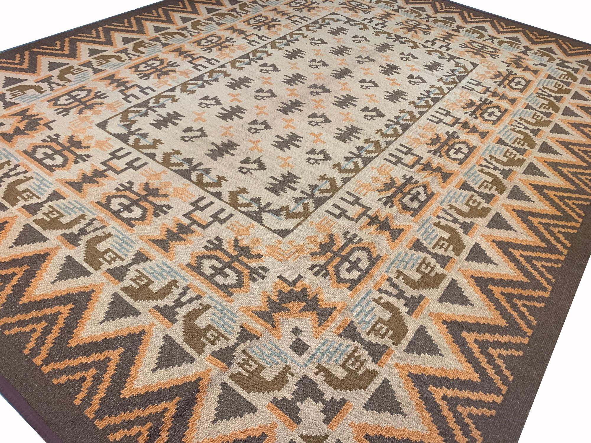 This Scandinavian style Kilim rug was woven by hand in Sweden in the 1930s. Woven with a bold geometric design with accents of beige, cream light blue and orange, this is then framed by a zig-zag border woven in brown and orange. This oriental