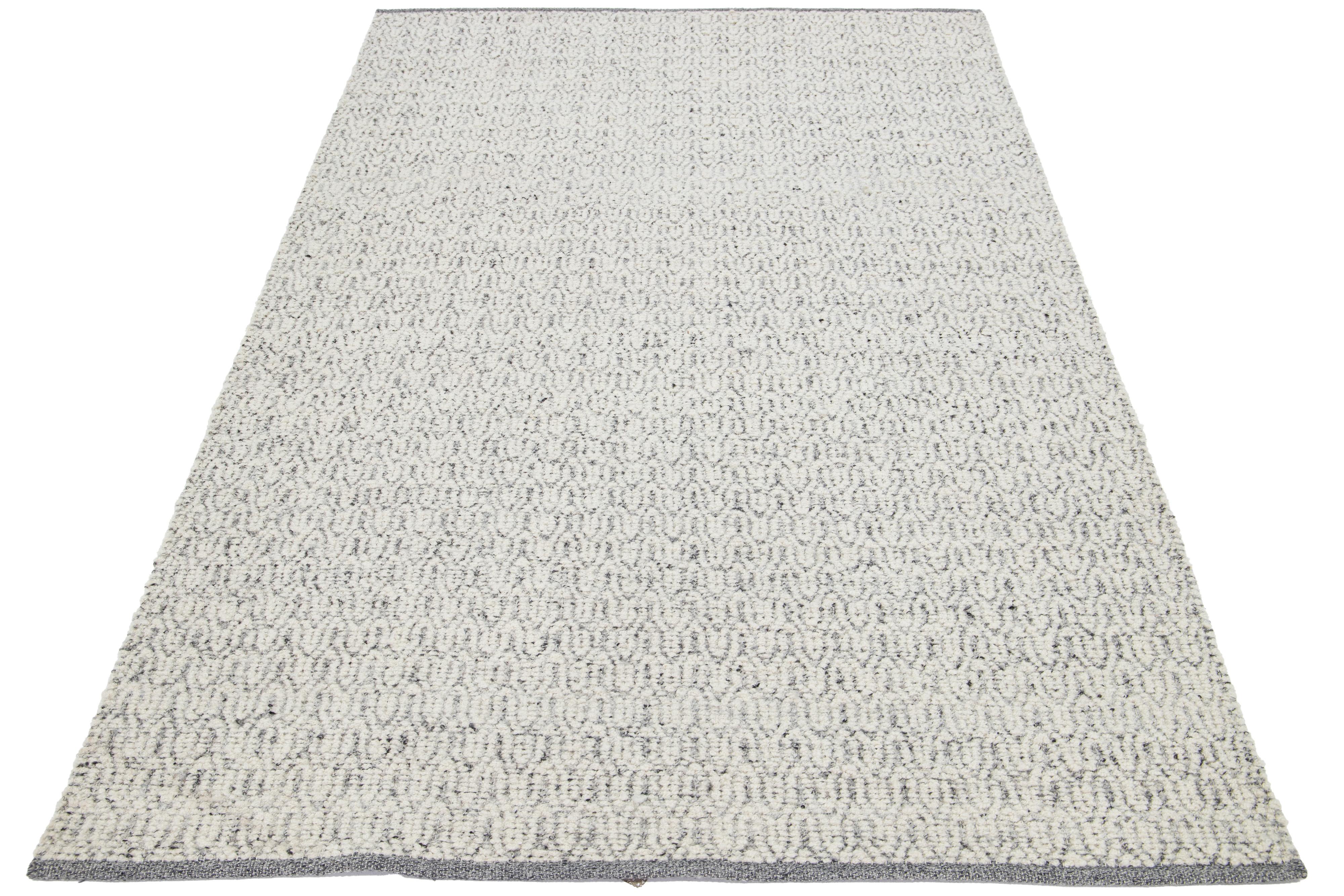 Questo bellissimo tappeto in lana lavorato a mano dalla texture moderna, che fa parte della nostra collezione Sasco, presenta un campo grigio con accenti avorio. Il tappeto vanta anche uno splendido disegno strutturato che ricorda i