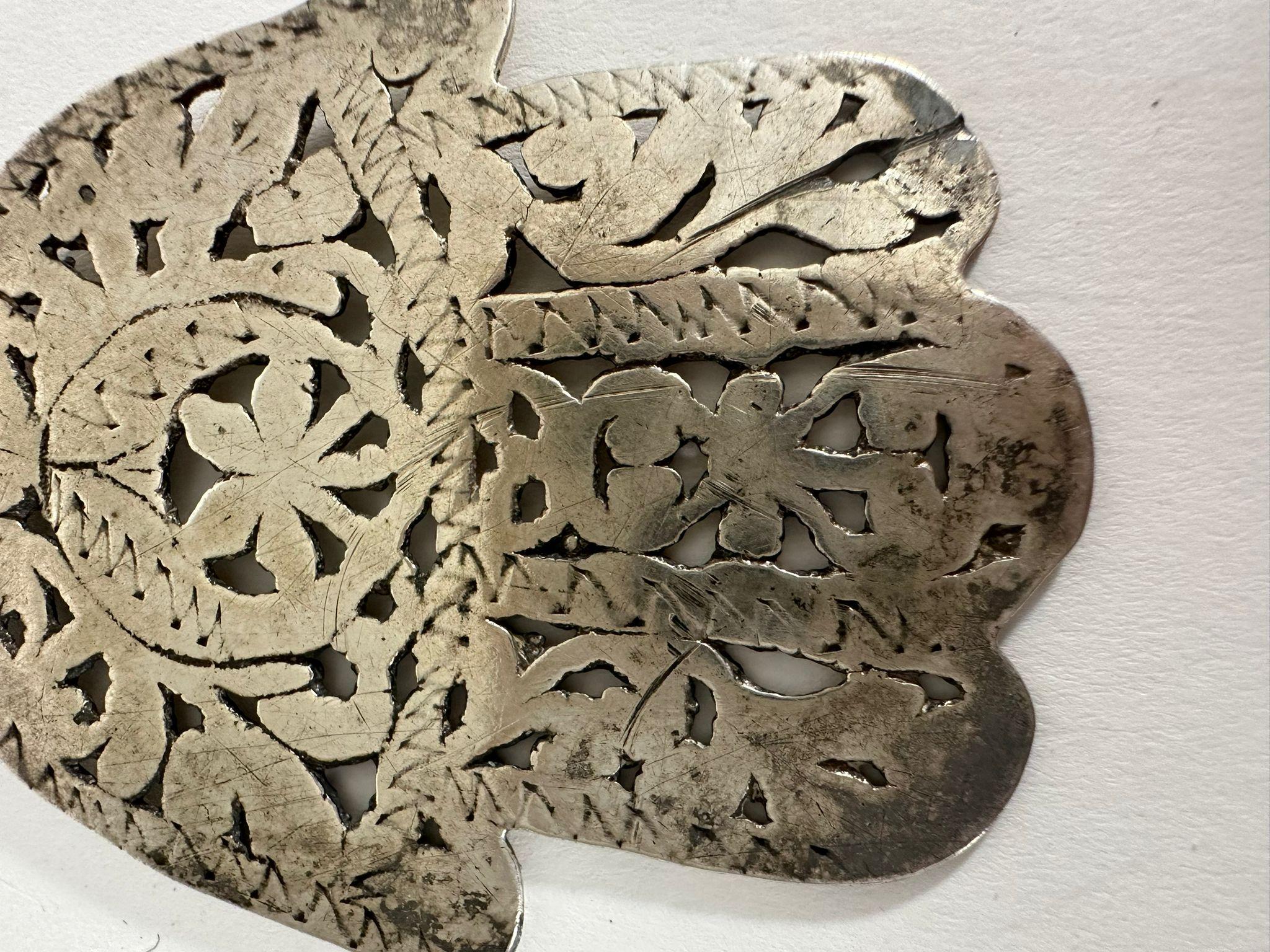 This handmade silver Hamsa necklace is a striking example of traditional Judaica from the Jewish communities of Tunisia. The Hamsa, a deeply rooted symbol in Sephardic and North African Jewish culture, is intricately crafted with delicate openwork