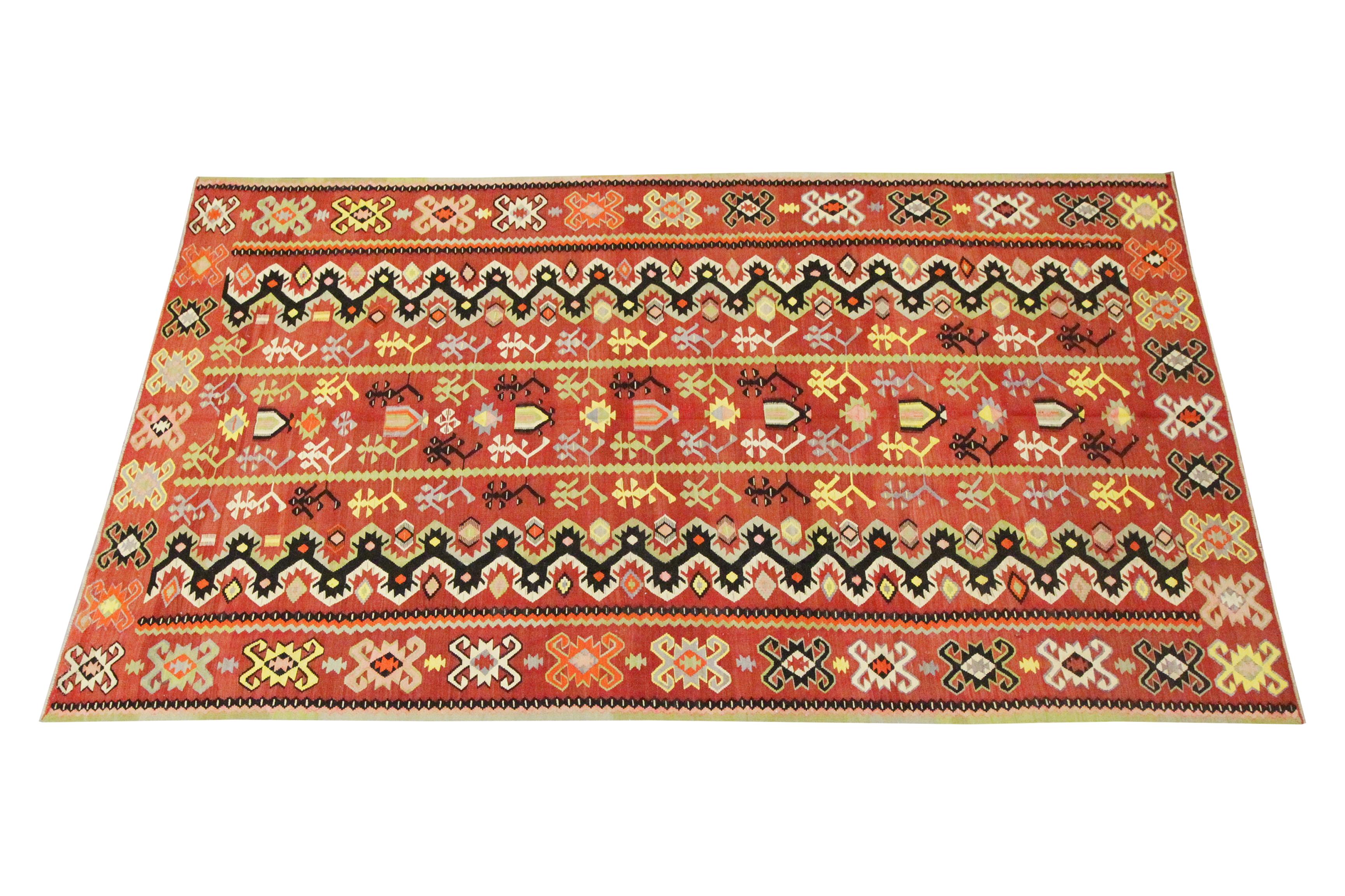 This antique tribal kilim is a bold accent rug woven with elegance and delicacy. This kilim has been woven with a rich red background with accents of black, yellow, green and light blue that make up the geometric tribal design in a symmetrical