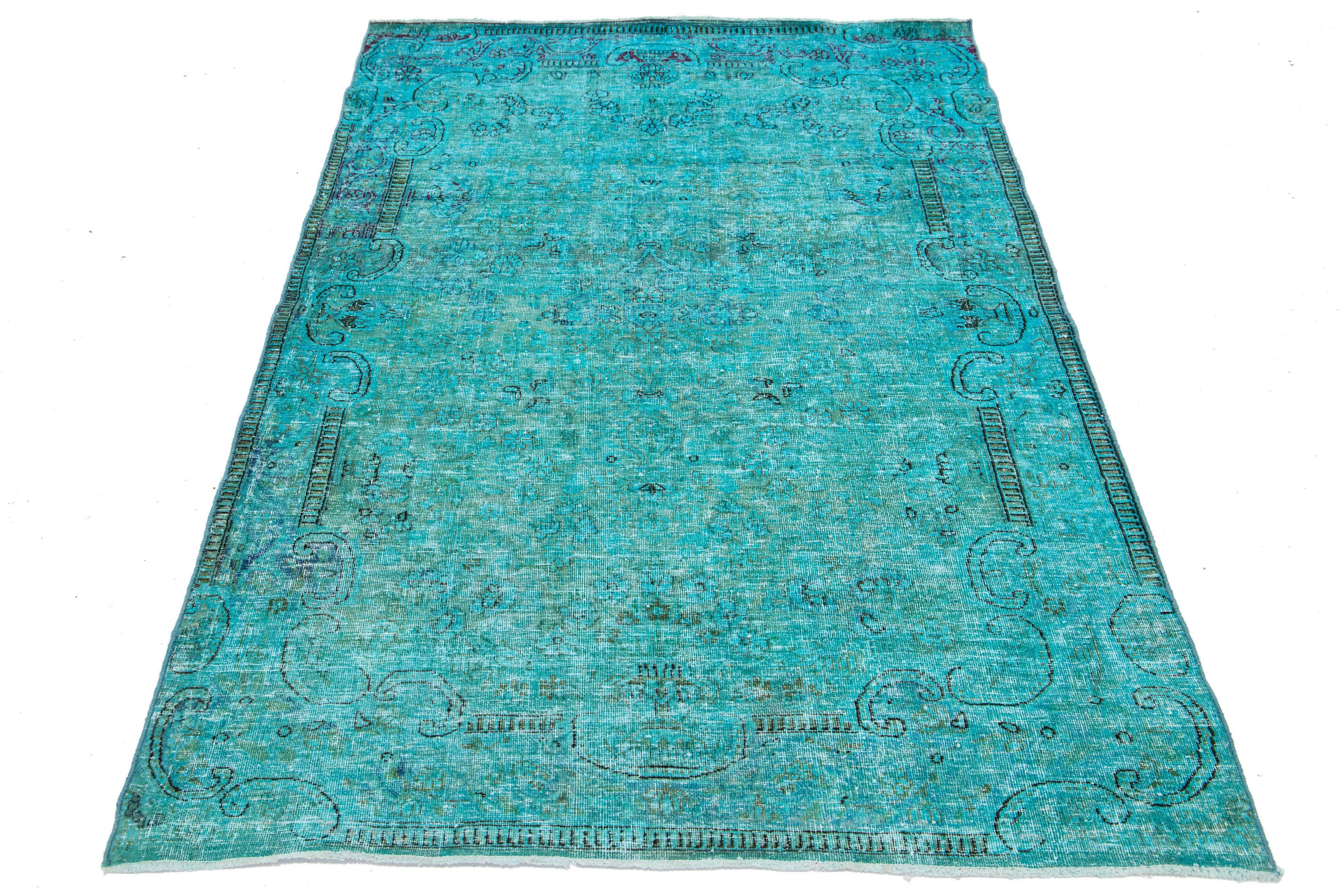 Ce tapis vintage en laine persane surteinte présente un champ turquoise captivant avec de charmants accents floraux gris.s.

Ce tapis mesure 3'9