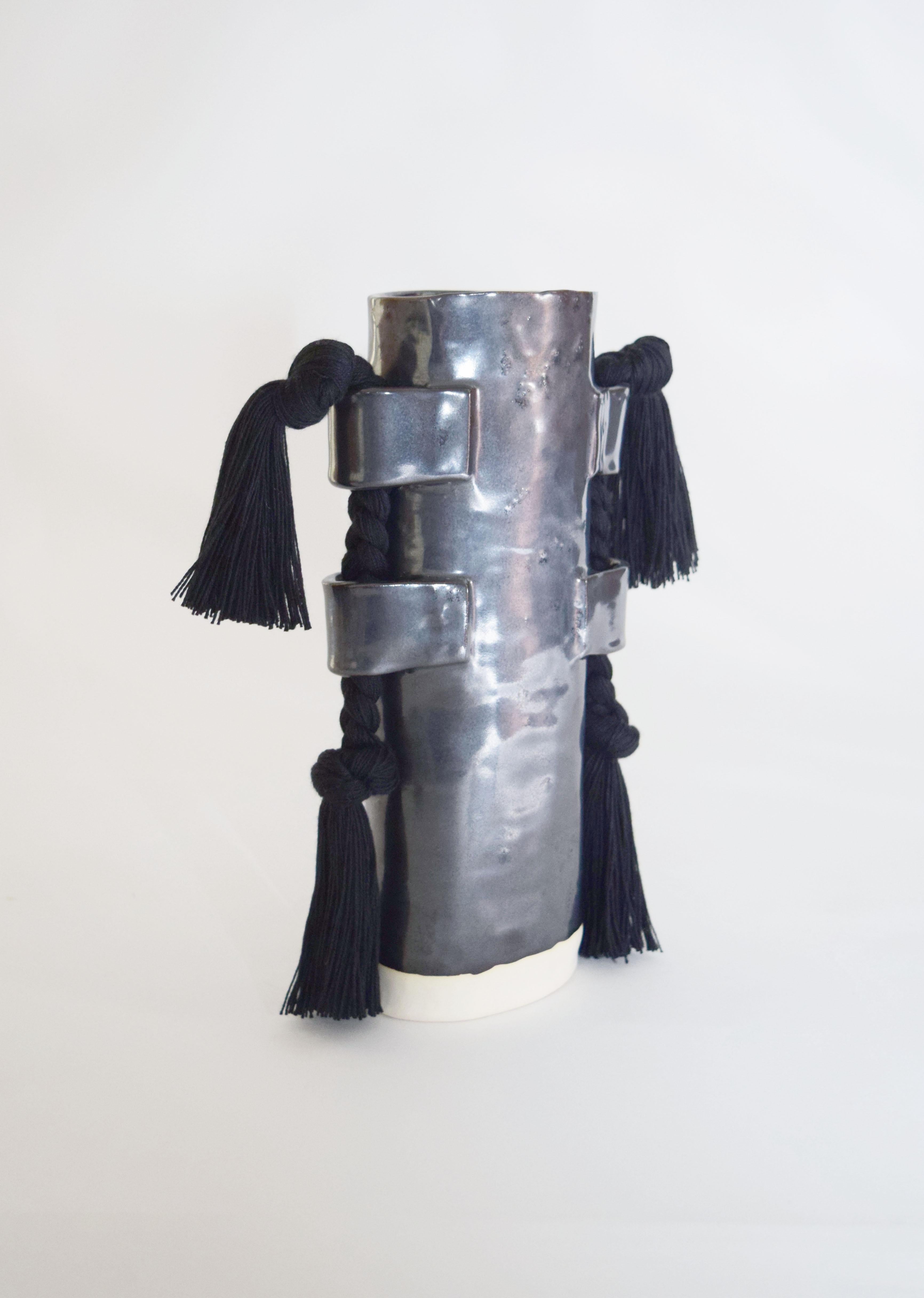 Vase #504 by Karen Gayle Tinney

Hand formed stoneware vase with black glaze. Inside is glazed black and will hold water - please take care not to damage fringe areas. Black cotton fringe braids with fringe are applied to the outside of the vase.