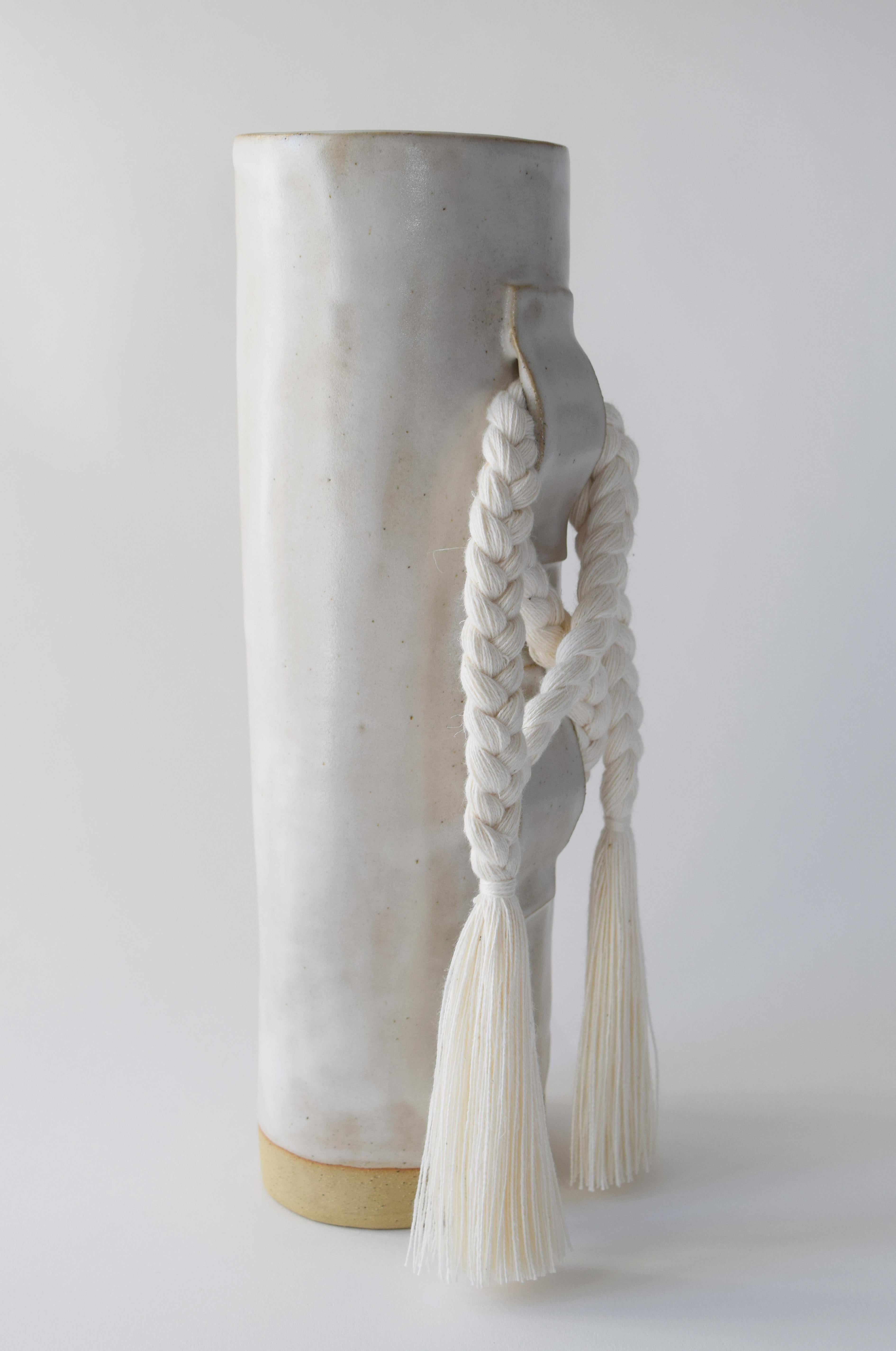 Vase #696 by Karen Gayle Tinney

Featuring a large gestural knot, this vase takes inspiration from the braided details of Karen’s one of a kind wall sculptures.

Hand formed stoneware with satin white glaze. White cotton braided details (braid is