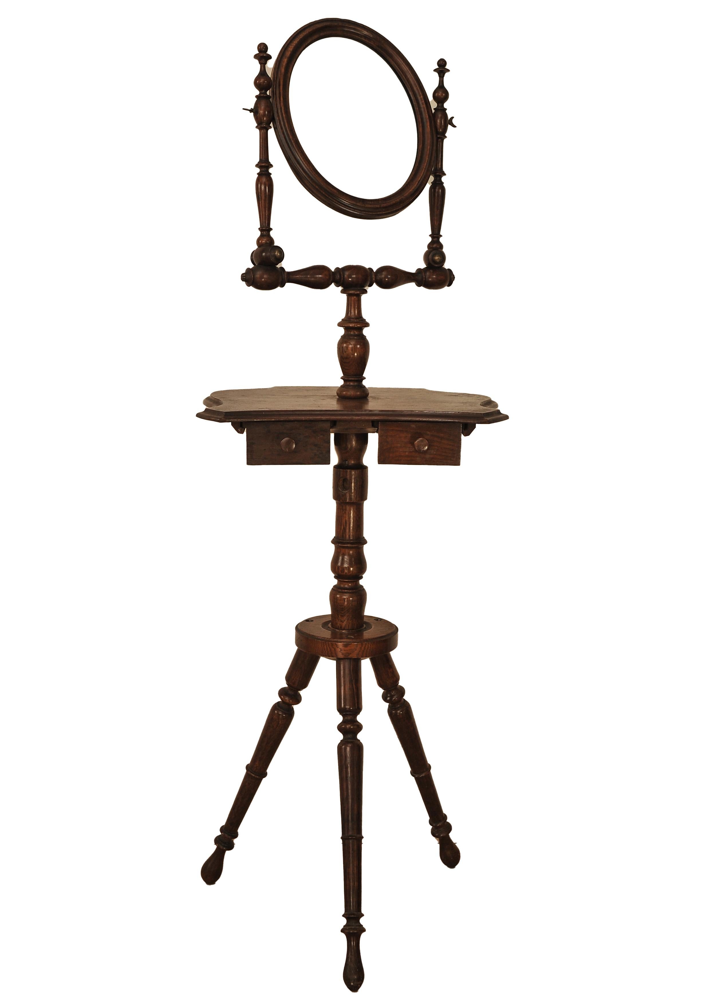 A Handmade Victorian Oak Shaving Stand, With A Pivotable Oval Mirror On Turned Supports Above An Inverted Shaped Middle Section With Two Frieze Drawers, Raised On A Turned Stem With Tripod Turned Legs.

An extremely well executed item, with brass