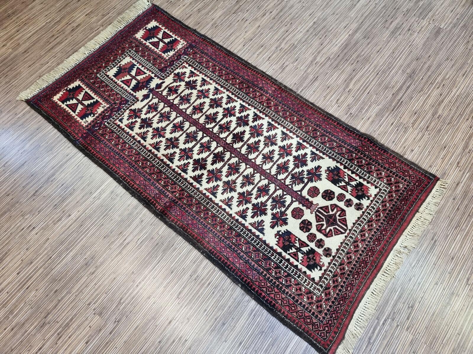Experience the beauty and elegance of this Handmade Vintage Afghan Baluch Prayer Rug, a stunning piece of art that reflects the rich cultural heritage and intricate craftsmanship of the Baluch people. This woolen rug, dating back to the 1950s,