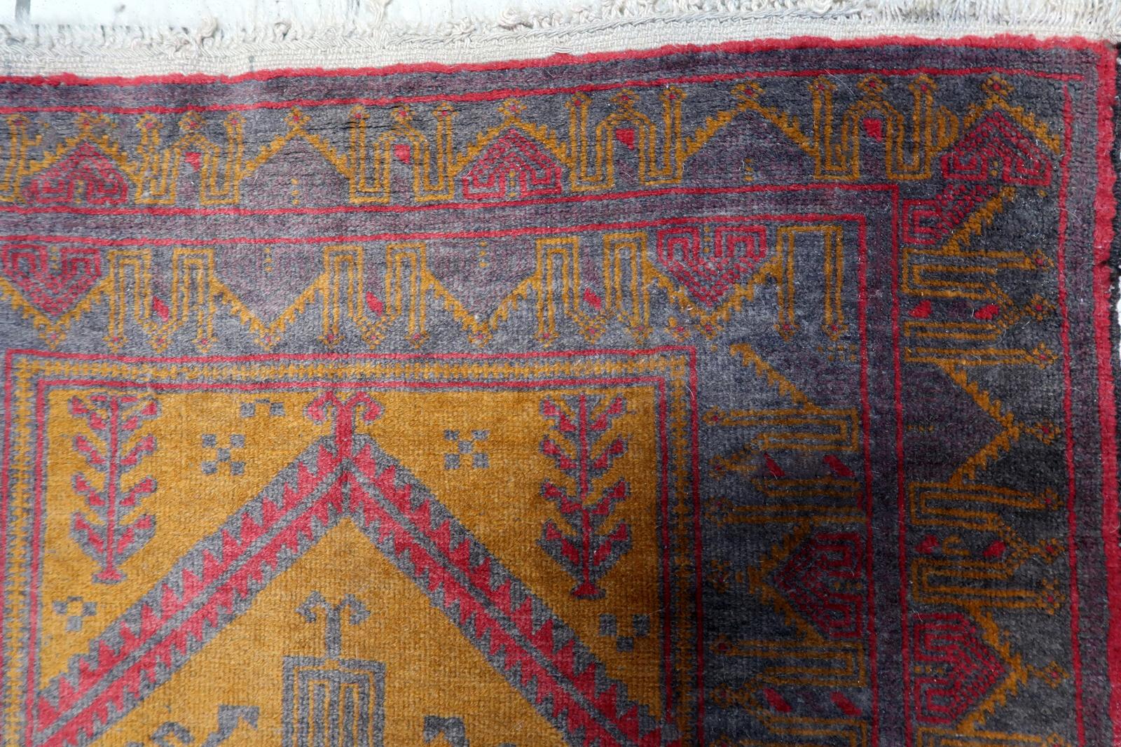 Wir stellen Ihnen unseren bezaubernden handgefertigten afghanischen Belutsch-Teppich aus den 1950er Jahren vor. Dieser exquisite Teppich zeigt einen traditionellen Belutsch-Stil mit einer einzigartigen Mischung aus fuchsiafarbenen, orangefarbenen