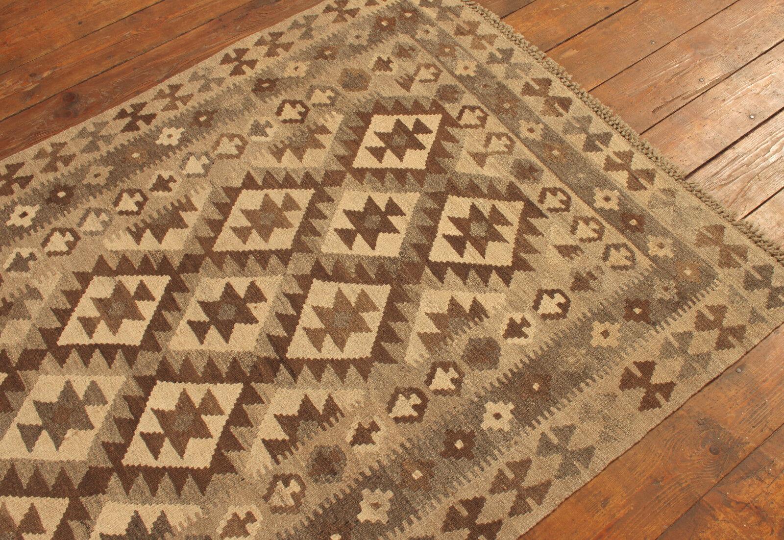  Immerse your space in the timeless charm of our Handmade Vintage Afghan Flatweave Kilim, a unique piece from the 1980s. Measuring at 3.9' x 6.3', this kilim boasts beige and brown shades in a captivating geometric design, adding warmth to your