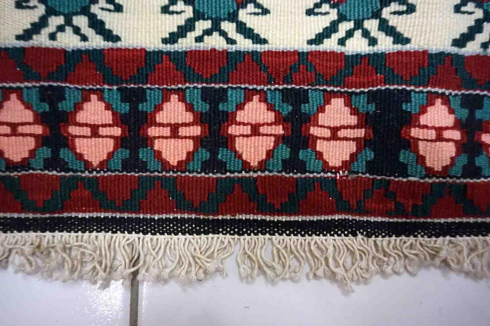 Add a touch of unique style to your home decor with this Handmade Vintage Persian Ardabil Kilim. This beautiful rug features a classic Ardabil style design with beige, red, green, and black background colors that will complement any room's color