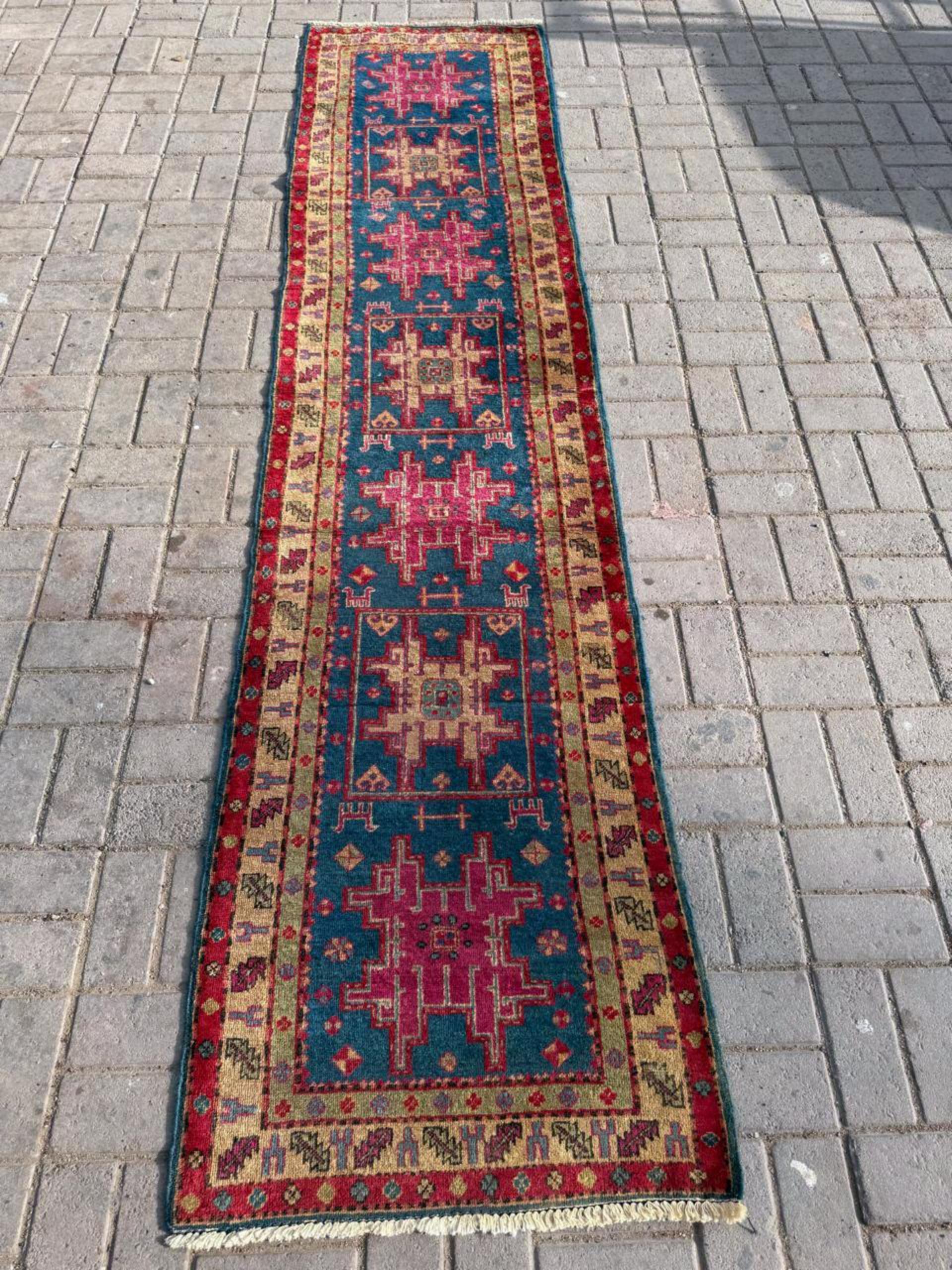 Setzen Sie mit diesem exquisiten, handgefertigten kaukasischen Kazak-Läufer im Vintage-Stil einen kräftigen Farbtupfer mit Stammeskunst. Dieser aus den 1950er Jahren stammende Läufer ist ein Beweis für die anhaltende Anziehungskraft traditioneller