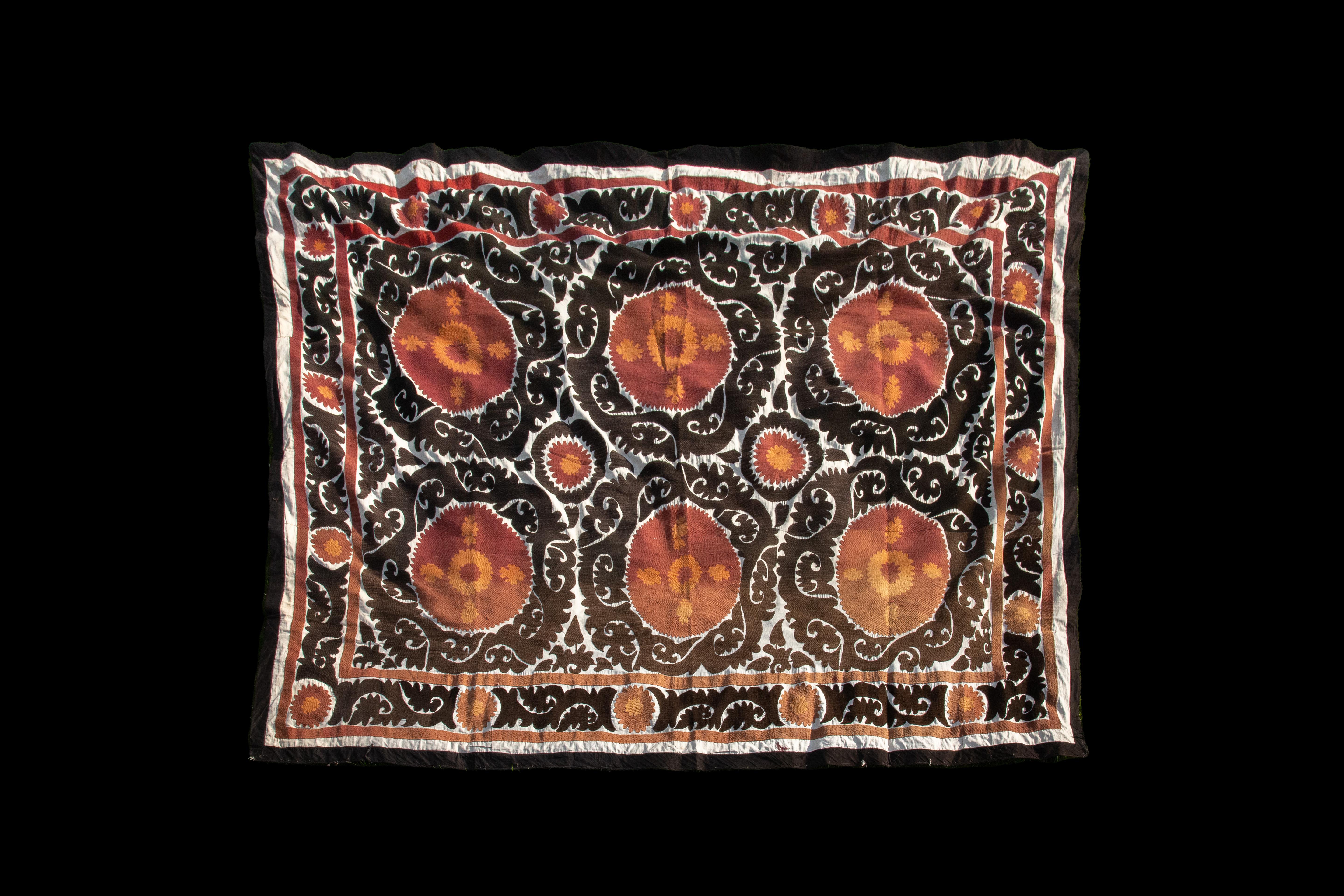 Handmade Vintage Cotton Suzani, Orange, and Charcoal

Richly hand-embroidered vintage Uzbek suzani in iconic black and copper oranges.
Sun burst flowers are ringed with black scrolls on natural cotton.
Cotton embroidery in tight stitches give a
