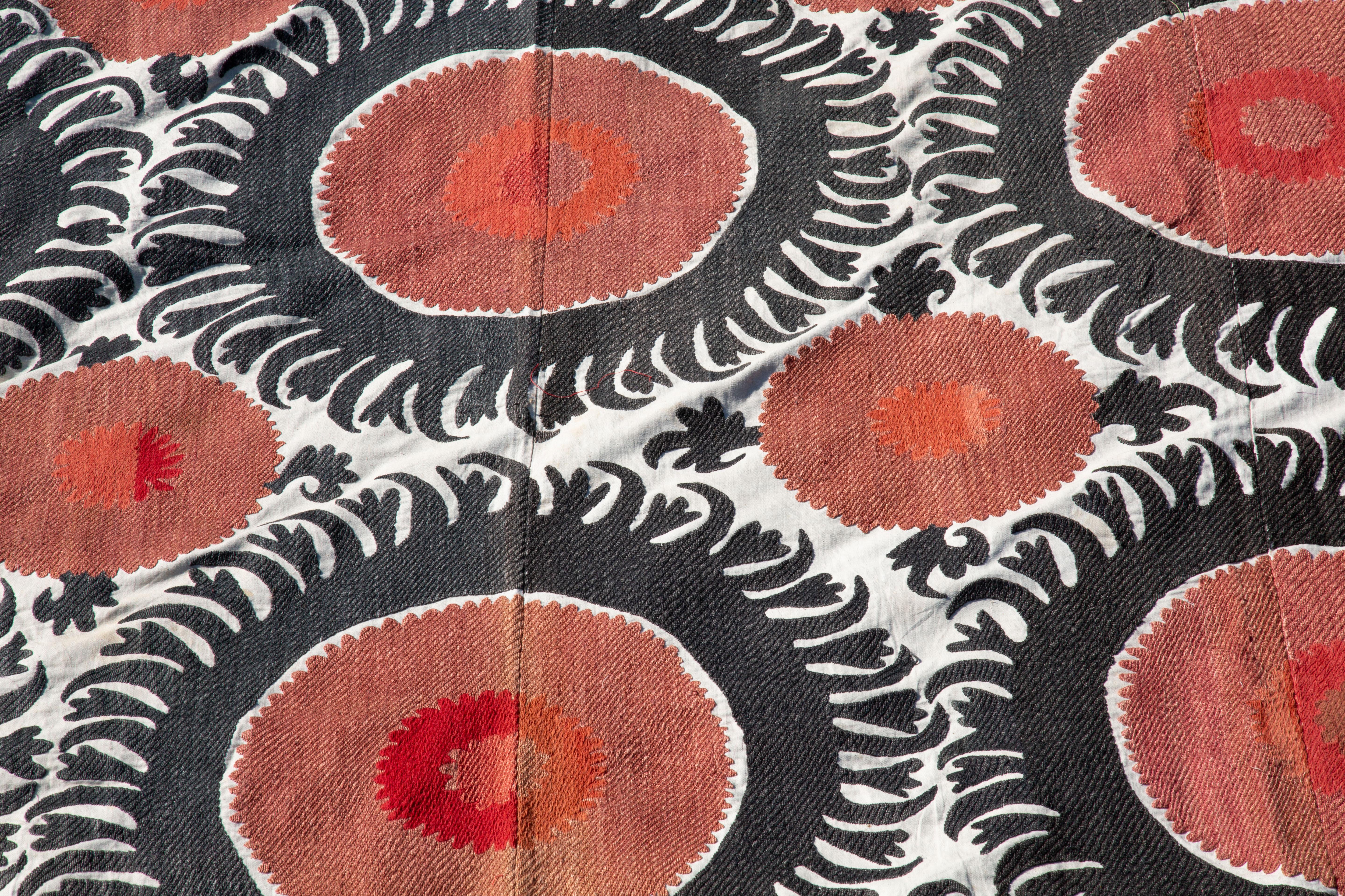 Handmade Vintage Cotton Suzani, Red, and Charcoal geometric designs.

Richly hand-embroidered vintage Uzbek suzani in iconic black and copper oranges.
Sun burst flowers are ringed with black scrolls on natural cotton.
Cotton embroidery in tight