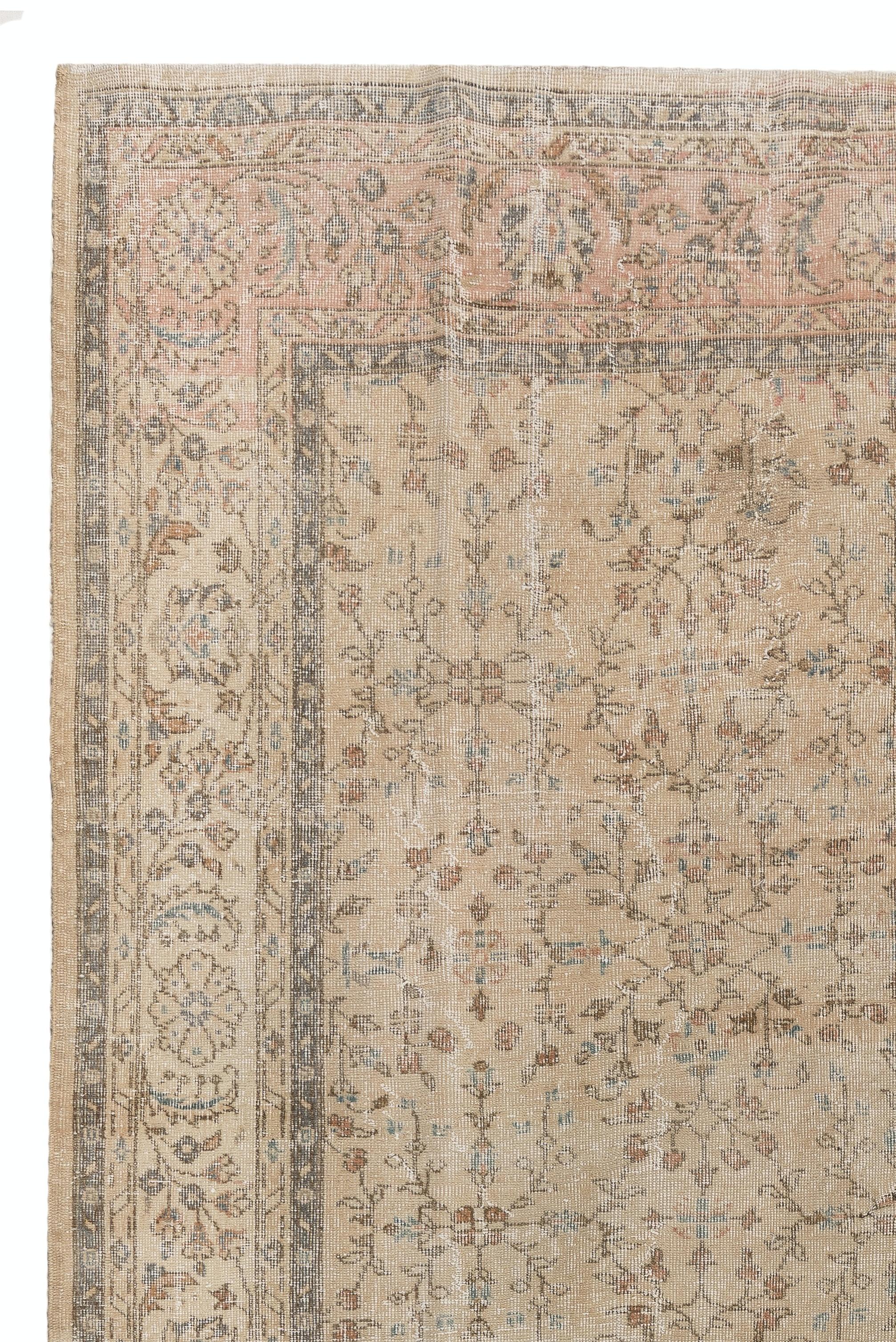 This vintage area rug was hand knotted in Turkey in 1960s. It is 7.4 x 10.4 ft and it features an all-over floral on a beige background. It is deep-washed, clean as a brand new rug, has distressed low wool pile on finely woven cotton foundation. It