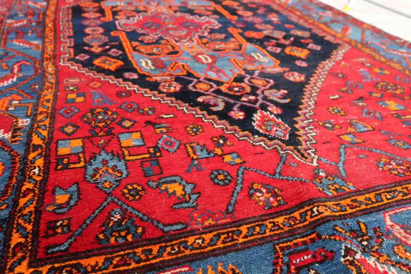 Handmade vintage Middle Eastern rug in red and blue shades. The rug has been made in wool in the middle of 20th century. It is in original condition, it has some low pile. The design on the rug is unusual, medallion is not even.

-condition: