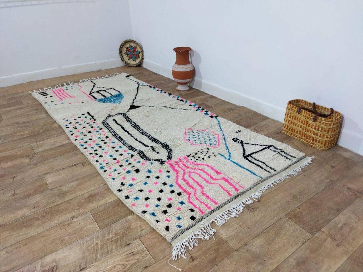 Dieser atemberaubende, handgefertigte marokkanische Berberteppich aus den 1980er Jahren zeigt die traditionelle Berberkunst mit seinen geometrischen Motiven und kühnen schwarzen Mustern auf einem natürlichen, beigen Wollgrund. Der Teppich wurde nie