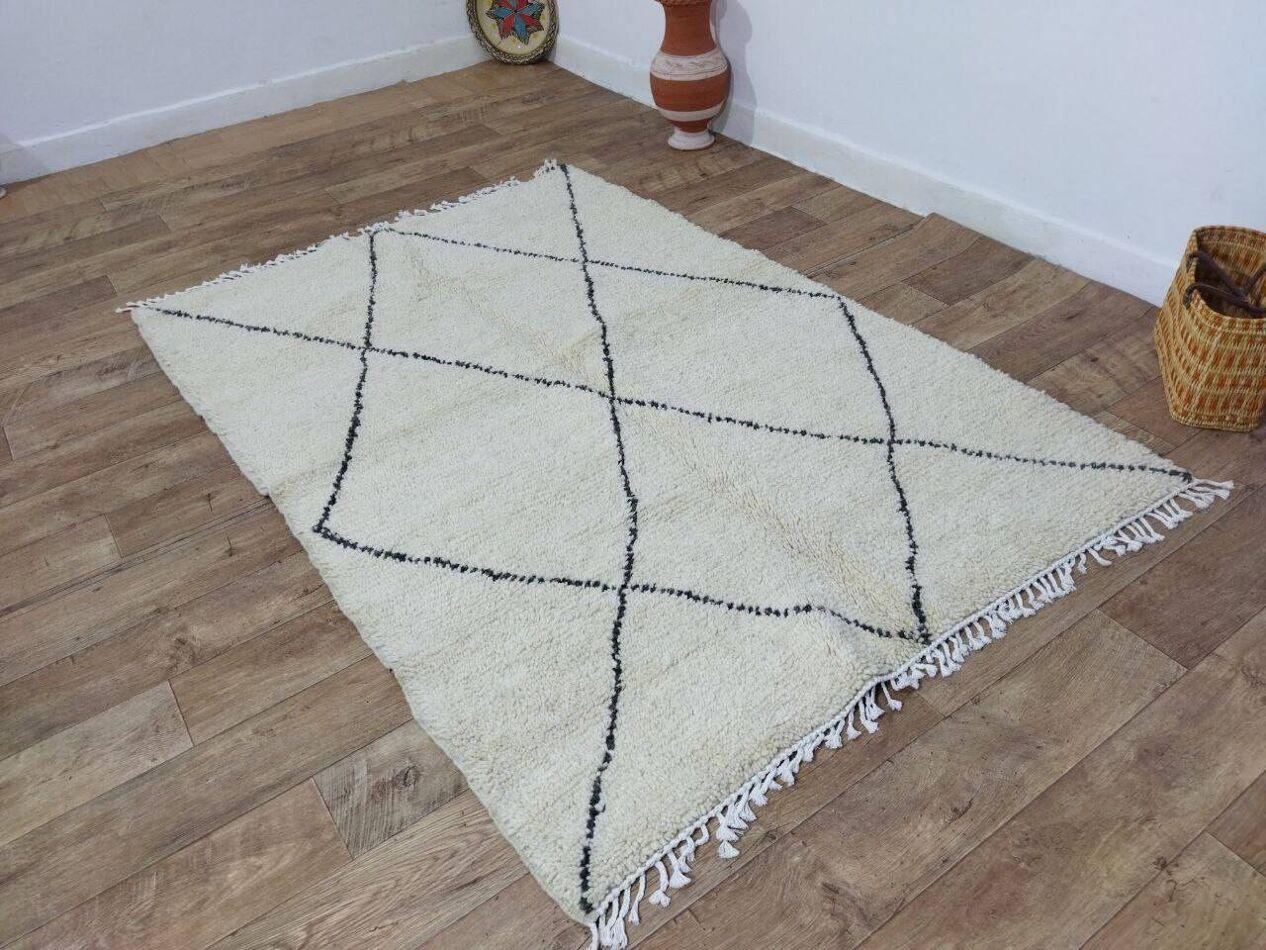 Ce tapis berbère marocain vintage, fabriqué à la main dans les années 1980, capture l'essence de l'artisanat berbère traditionnel. Fabriqué en laine douce de haute qualité, il reste en excellent état, n'ayant jamais été utilisé, préservant ainsi sa