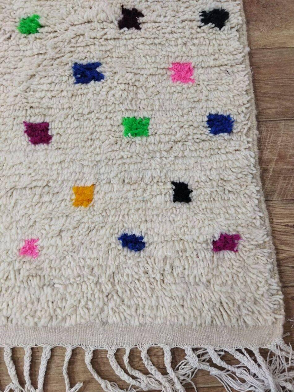 Ce tapis berbère marocain vintage, tissé à la main dans les années 1980, est un reflet étonnant de l'artisanat et de la tradition berbères. Fabriqué en laine douce de haute qualité, il reste en excellent état, n'ayant jamais été utilisé, ce qui