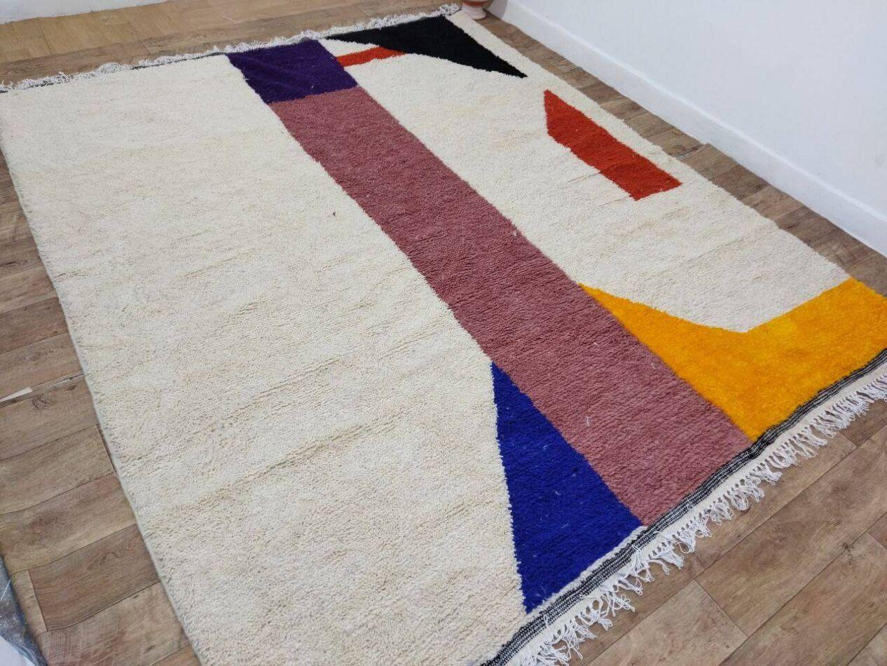 Ce superbe tapis berbère marocain, fabriqué à la main dans les années 1980, est une véritable représentation de l'art traditionnel nord-africain. Tissé avec 100 % de laine de haute qualité, il offre une texture exceptionnelle, à la fois douce et