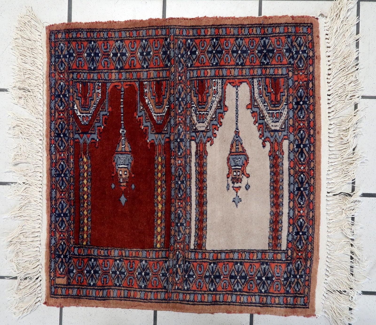 Handmade Vintage Pakistani Lahore Prayer Rug:

Design and Colors:
This square-shaped rug showcases intricate craftsmanship.
The dominant colors include:
Deep Reds: These warm tones evoke a sense of tradition and spirituality.
Blues: Interspersed