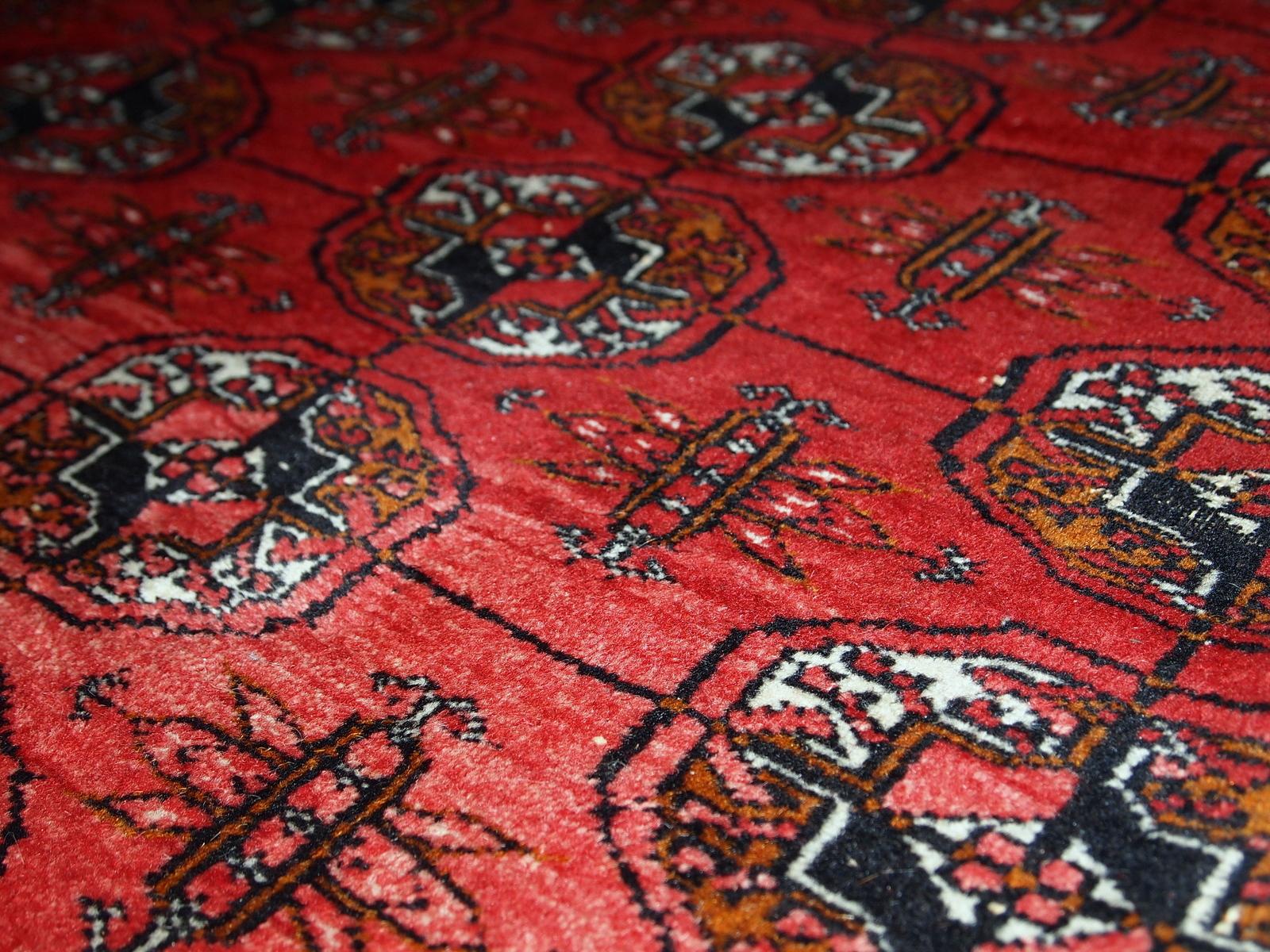 Handmade midcentury Pakistani rug in the style of Turkmen Tekke. Repeating elephant foot design on the bright red background. The rug has some signs of age but generally in original good condition.
 