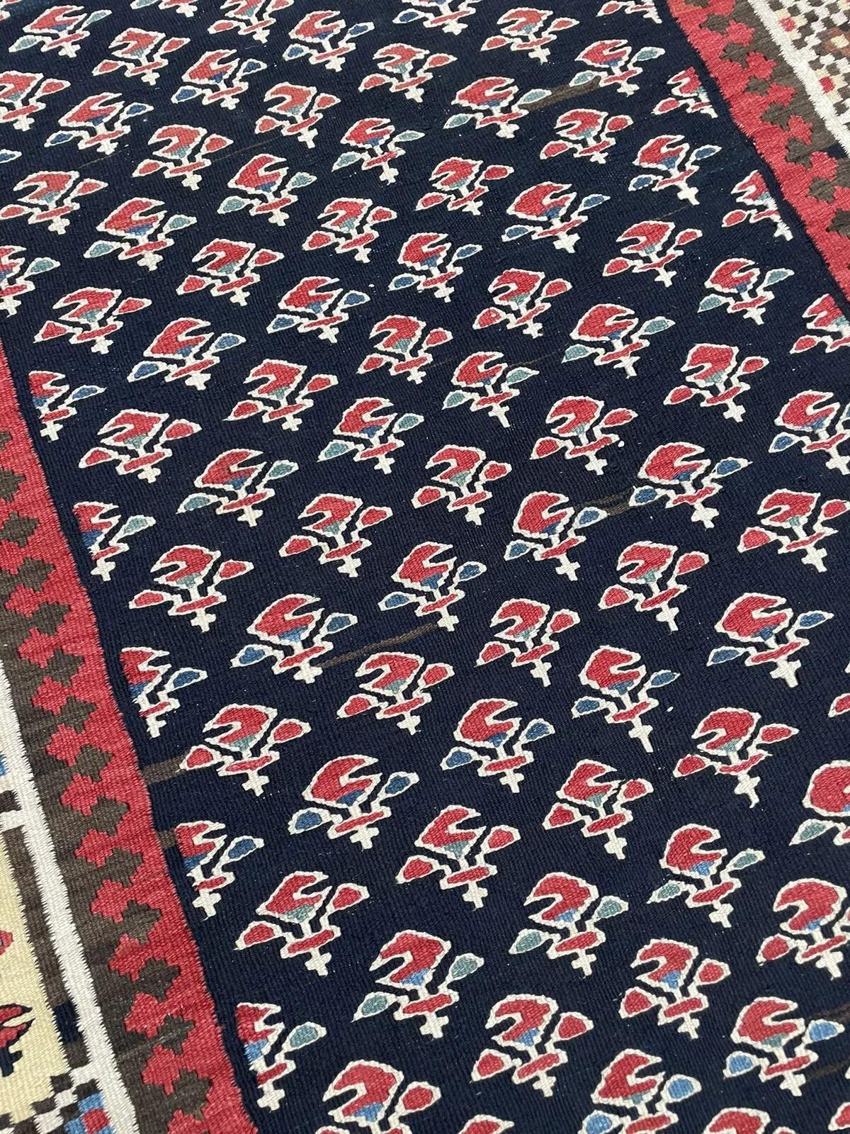 Tauchen Sie ein in die zeitlose Kunstfertigkeit dieses persischen Gashkai-Kelimteppichs im Vintage-Stil, ein Meisterwerk aus den 1970er Jahren, das mit außergewöhnlichem Geschick handgefertigt wurde. Dieser flachgewebte Teppich mit den Maßen 104 cm