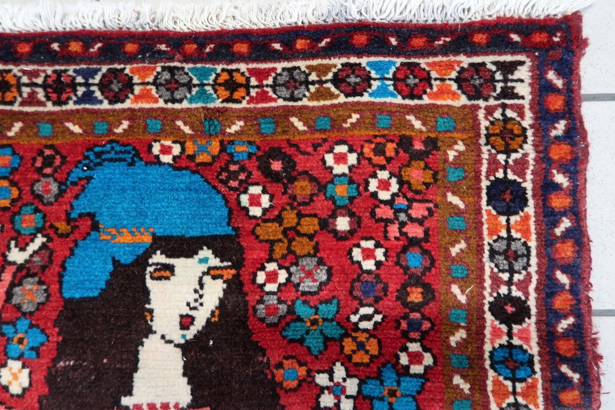 This vintage Persian Hamadan rug from the 1970s is a beautifully handcrafted piece, featuring a vibrant and artistic floral and figurative design. Woven with 100% wool, it boasts rich colors and intricate patterns, making it a striking addition to