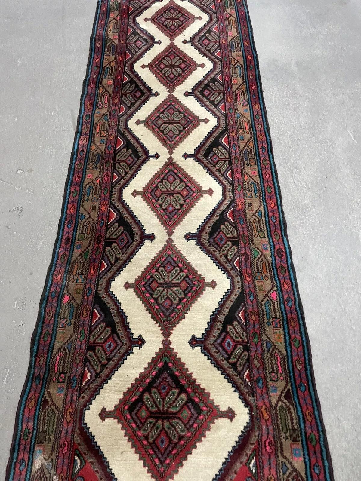 Ajoutez une élégance intemporelle à votre espace avec ce superbe chemin de table Hamadan persan vintage, fabriqué à la main dans les années 1970. Mesurant 2,46 x 10,99 pieds (75 x 335 cm), ce chemin de table en laine présente un motif géométrique