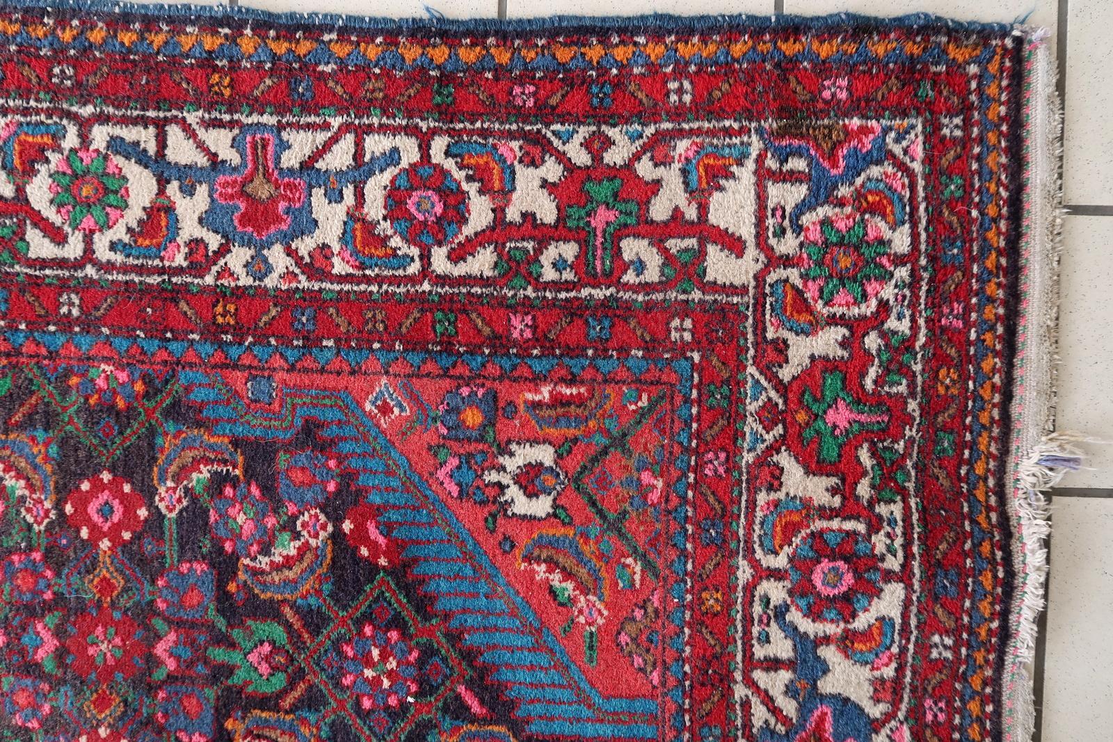 Dieser handgefertigte persische Malayer-Teppich aus den 1960er Jahren zeigt ein klassisches Medaillon-Muster in der Mitte, umgeben von komplizierten floralen und geometrischen Motiven. Die elegante Bordüre des in kräftigen Rot-, Marineblau- und