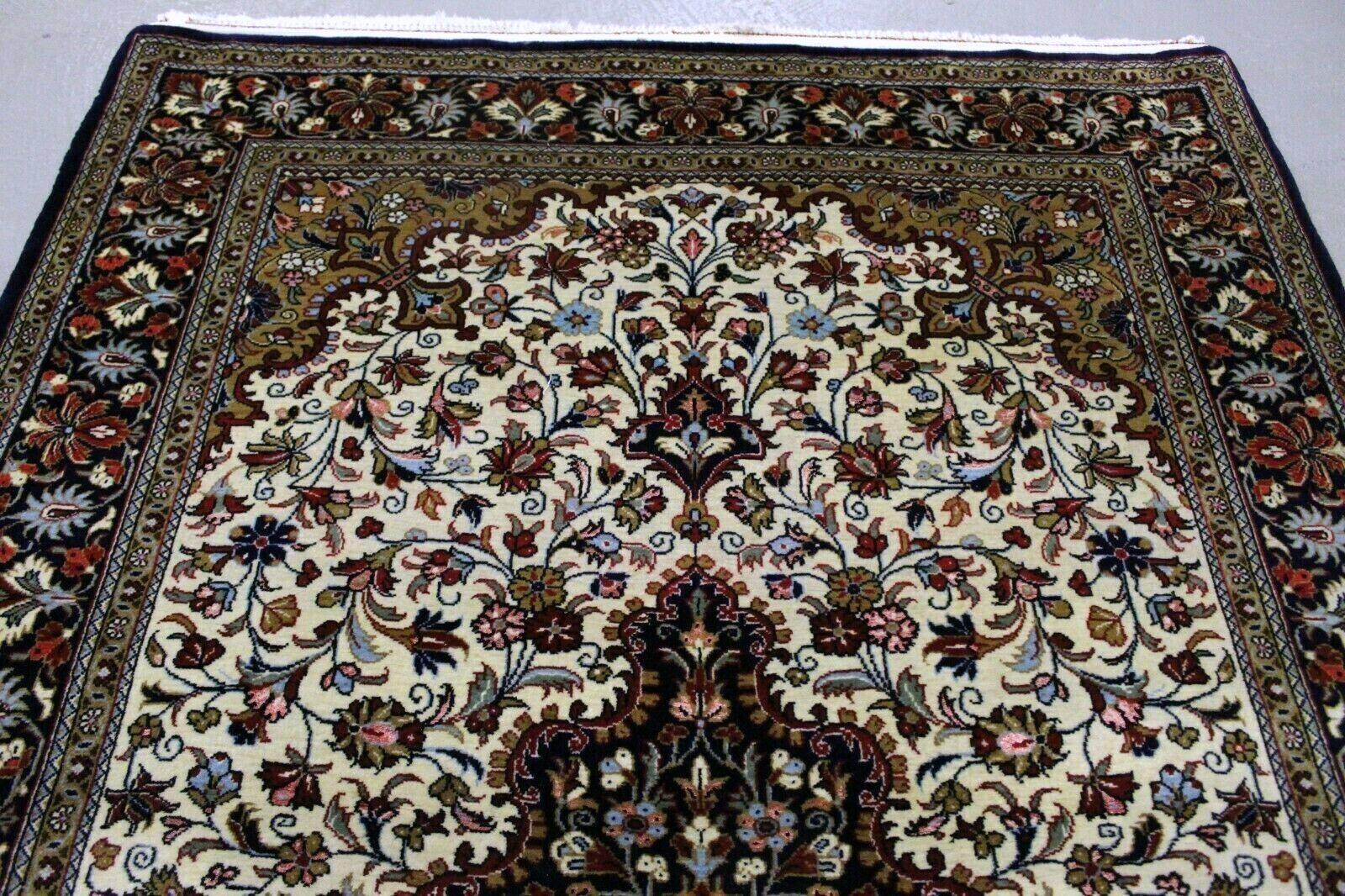  Wir stellen unseren exquisiten, handgefertigten Qum-Teppich im persischen Vintage-Stil vor, ein fesselndes Stück, das zeitlose Eleganz in jeden Raum bringt. Dieser Teppich aus den 1970er Jahren misst ungefähr 3,7' x 5,1' (115cm x 156cm) und ist