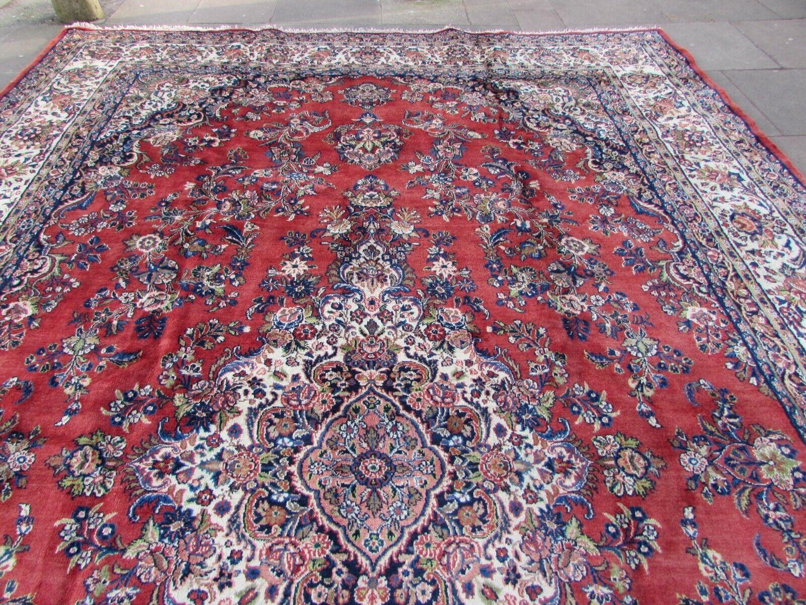 Lassen Sie sich von der Anmut und Tradition der persischen Kunst mit diesem handgefertigten Sarouk-Teppich in Übergröße im persischen Vintage-Stil verzaubern. Dieser in den 1970er Jahren gefertigte Teppich besticht durch sein zeitloses Design und