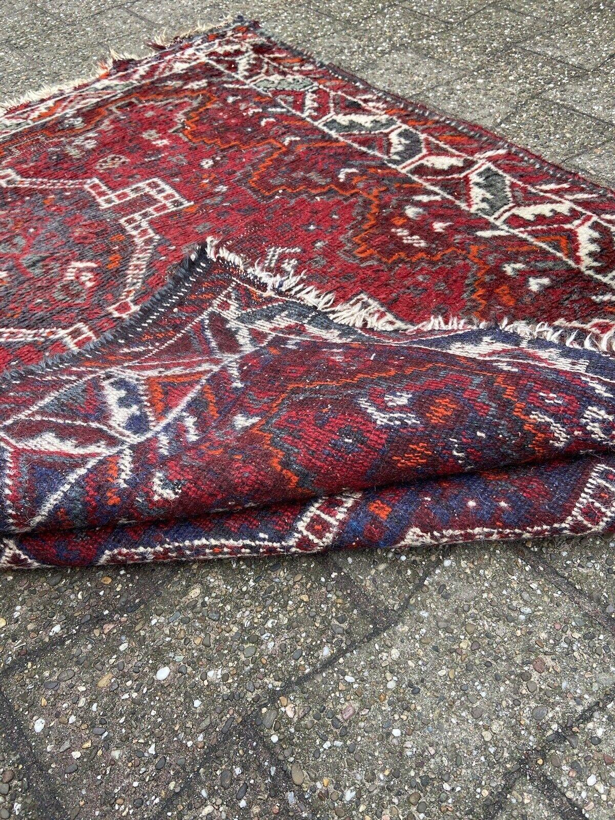 Nous vous présentons notre tapis Vintage Shiraz de style persan fait à la main, un morceau d'histoire des années 1940. Mesurant 3,9 pieds sur 5 pieds, ce tapis porte les marques du temps, avec quelques bouts manquants et des signes d'usure.