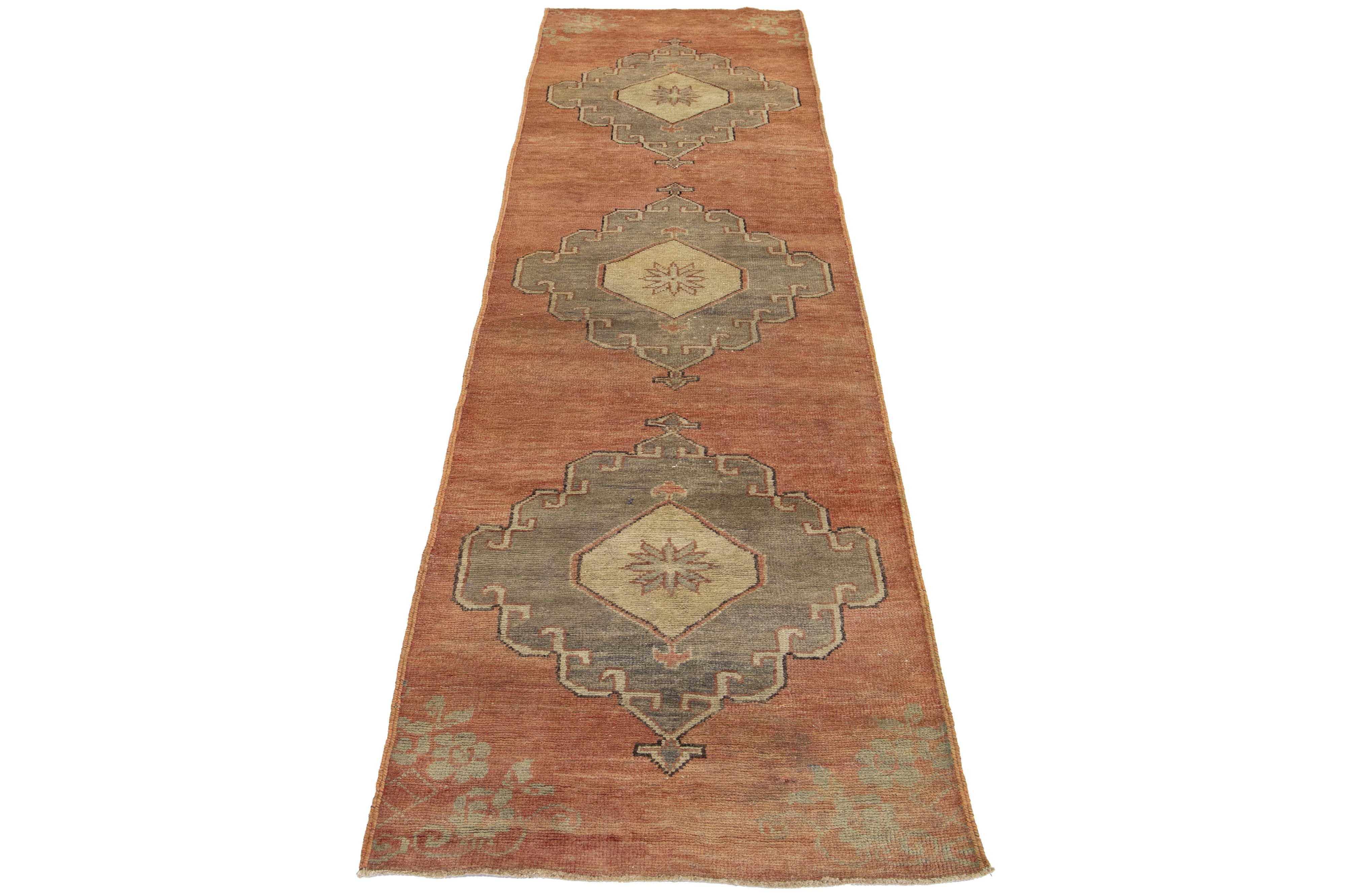 A beautiful vintage Turkish runner featuring a terracotta field and a tribal geometric design that covers the entire rug, with accents in gray and beige colors.

This rug measures 2' 7